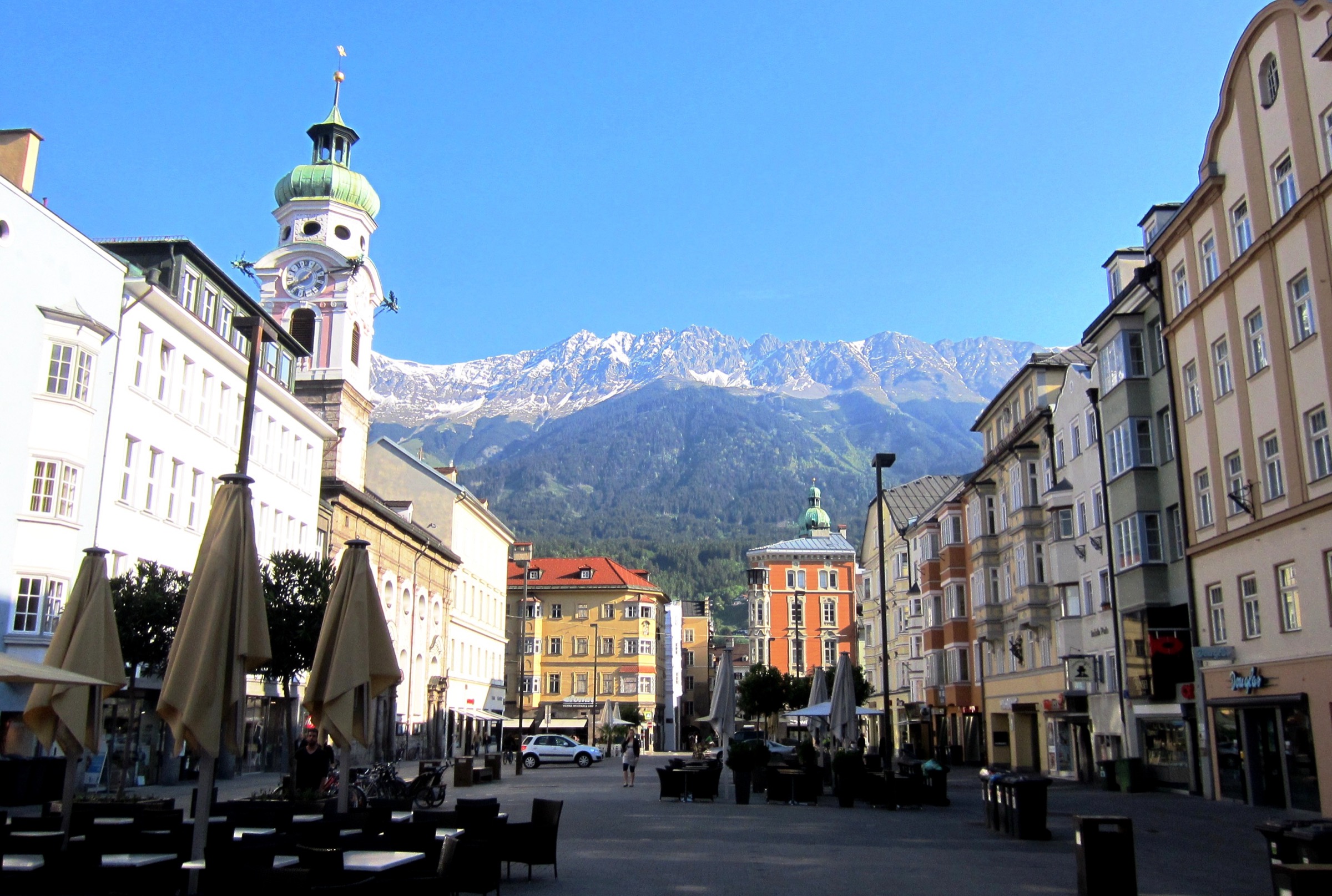Vue en enfilade de la Maria-Theresien-Straße dans le centre d'Innsbruck, avec la Nordkette enneigée s'élevant directement au-dessus de l'extrémité nord de la rue