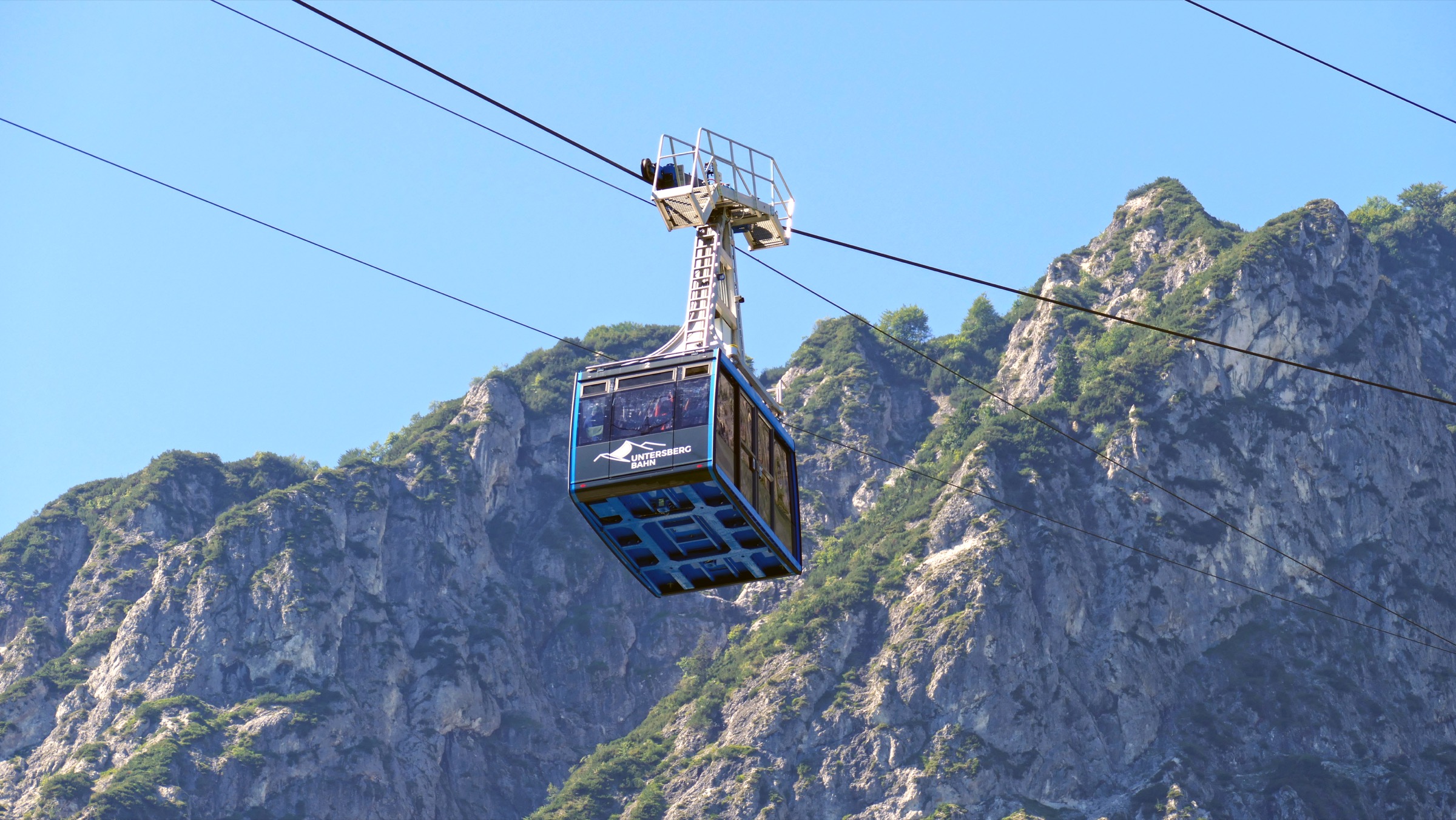 Une cabine rouge de l'Untersbergbahn grimpant au-dessus de la station de vallée boisée au sud de Salzbourg