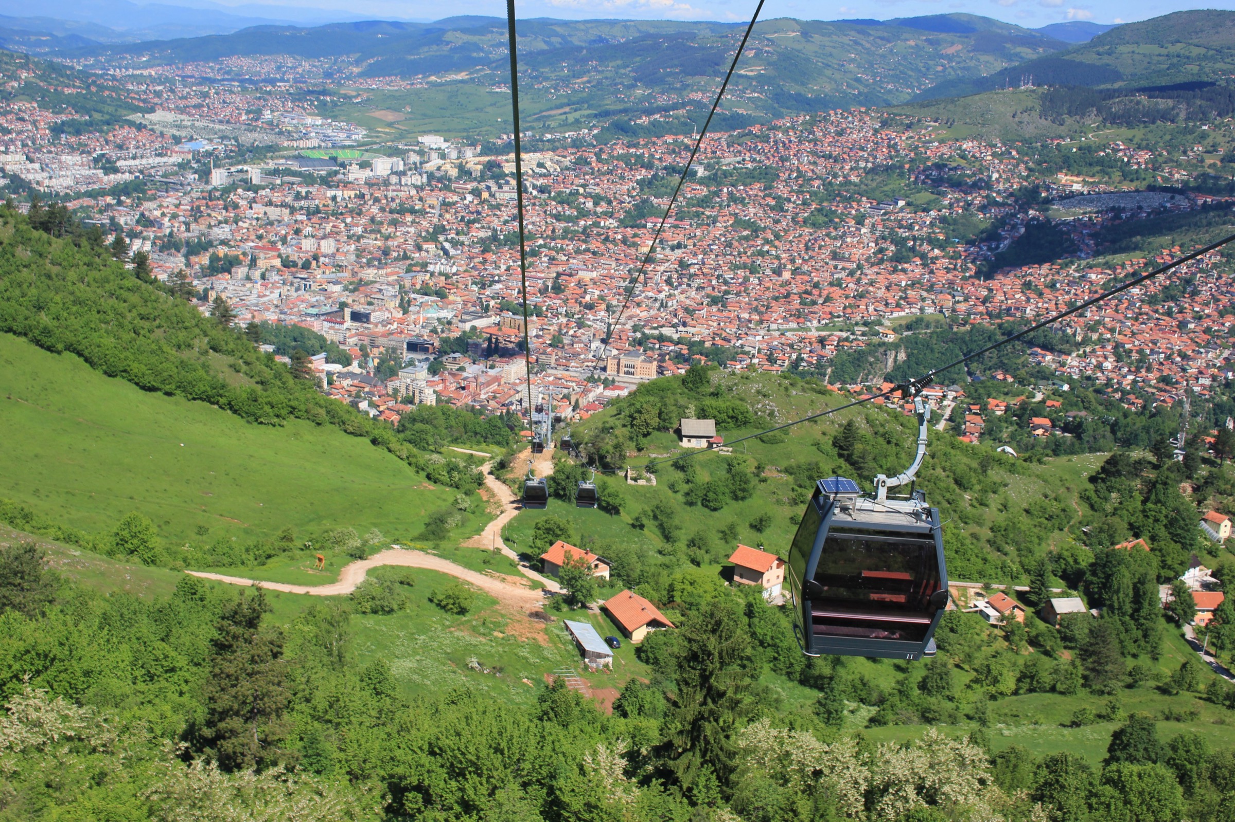 Une cabine du téléphérique de Trebević rouvert grimpant au-dessus des pentes boisées en lisière de Sarajevo