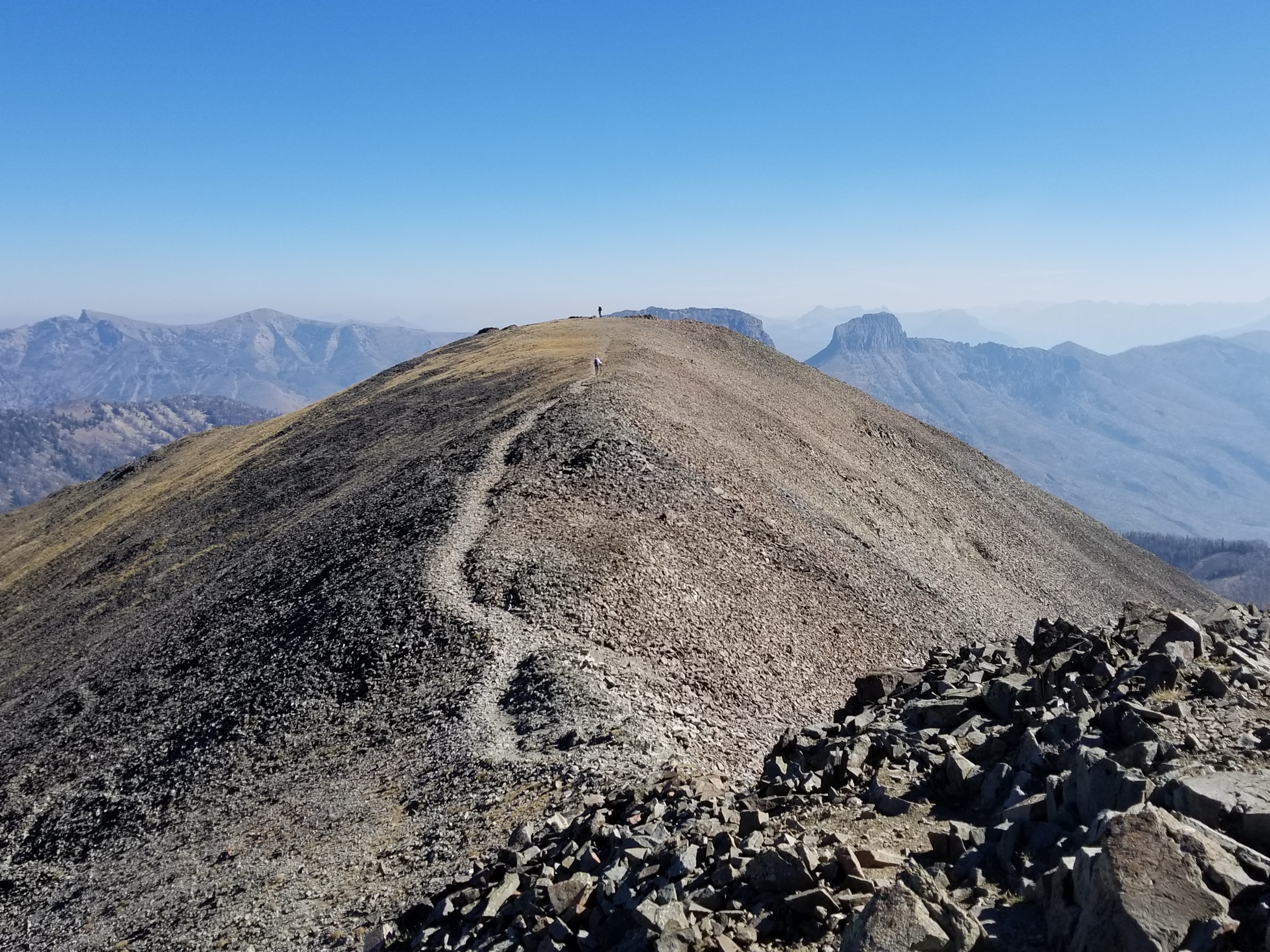 Hiker on the open summit ridge of Avalanche Peak, Yellowstone National Park, with the Absaroka Range in the background