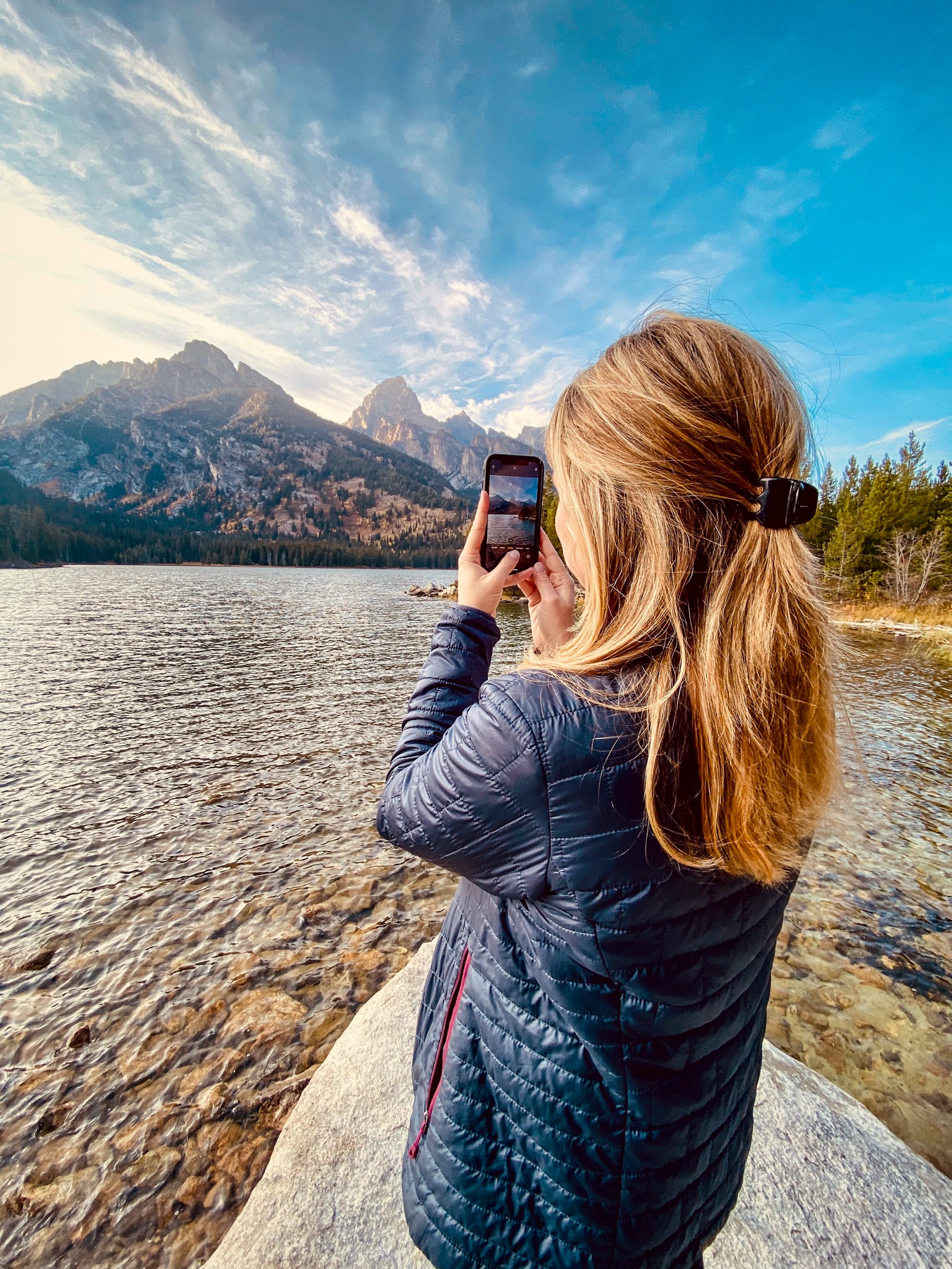 Visitor photographing the central Tetons from the shore of Taggart Lake, Grand Teton National Park