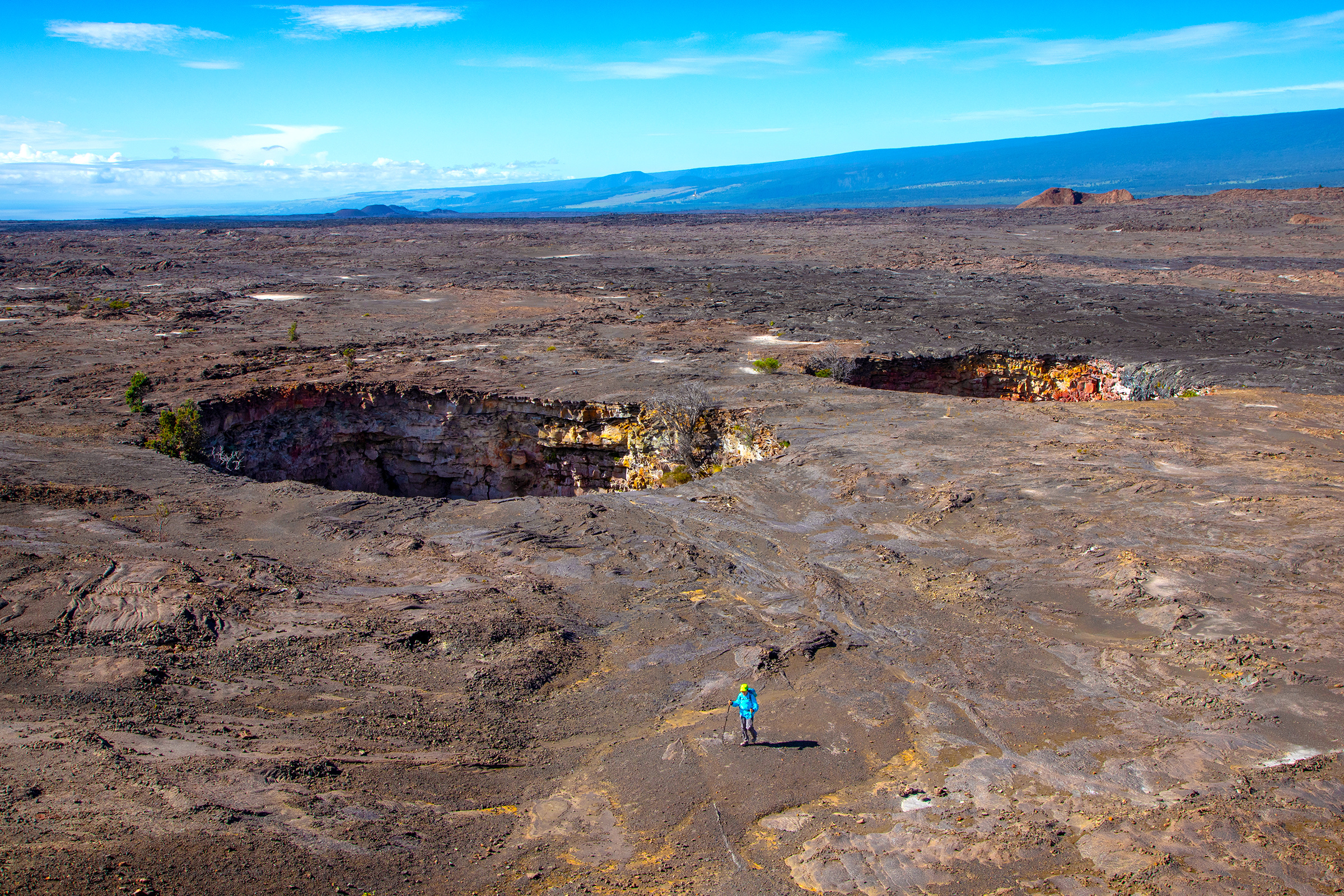 Hiker beside twin pit craters in the Kaʻū Desert section of Hawaiʻi Volcanoes National Park