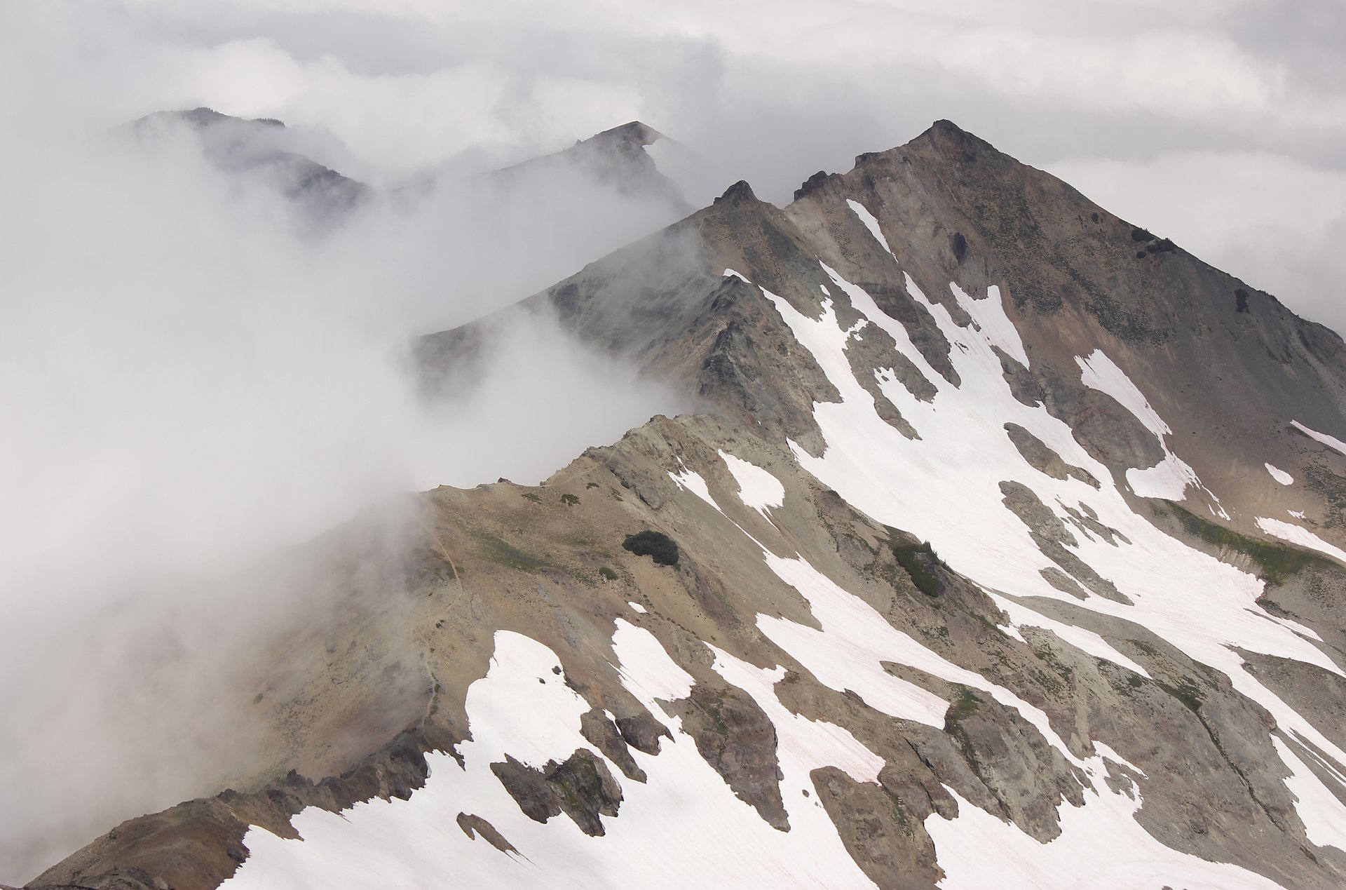 A thin footpath of the Pacific Crest Trail traversing a narrow rocky ridge north of Old Snowy Mountain
