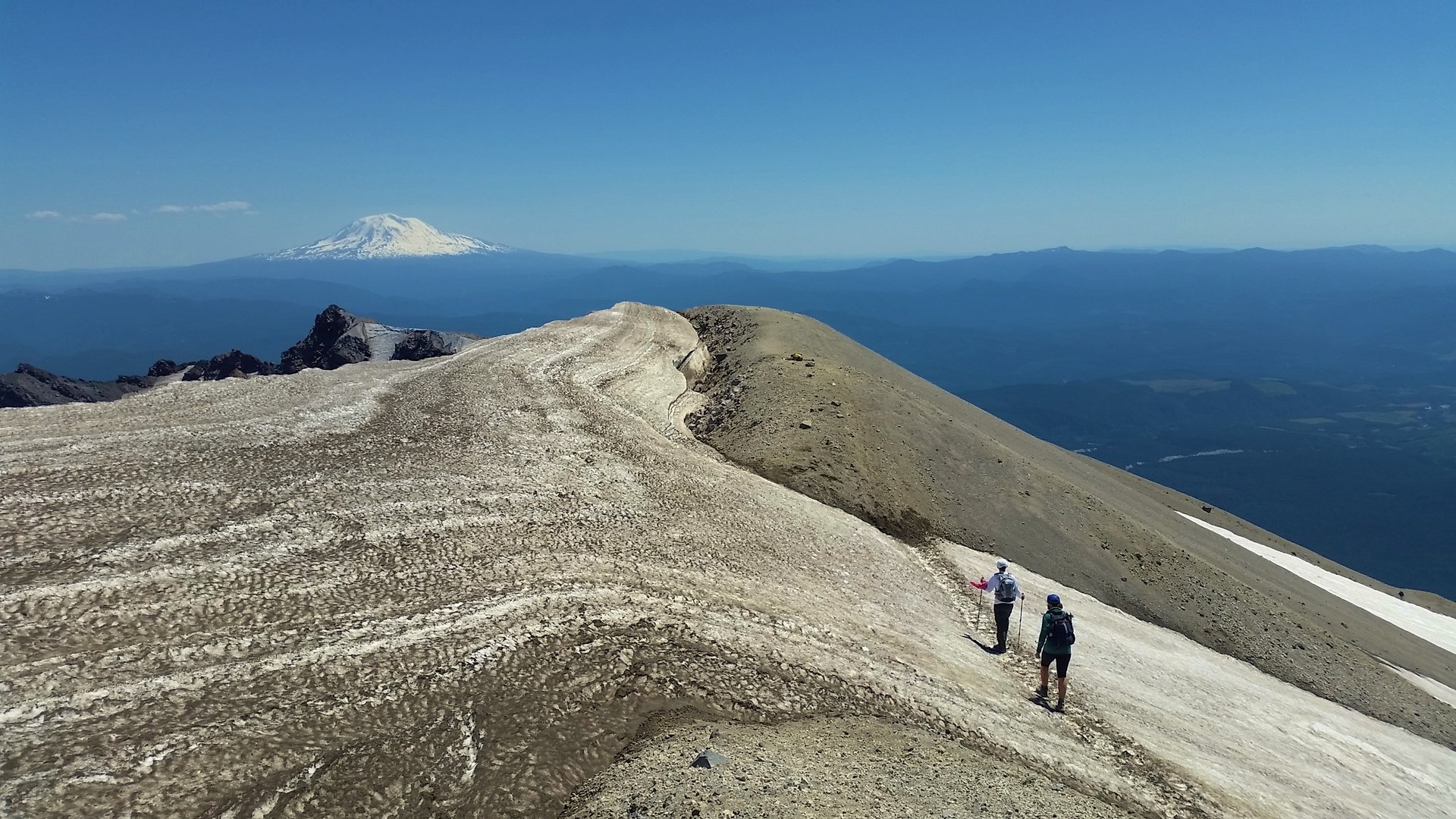 Le bord du cratère du Mount St Helens vu depuis le sommet, avec le Mount Adams au loin