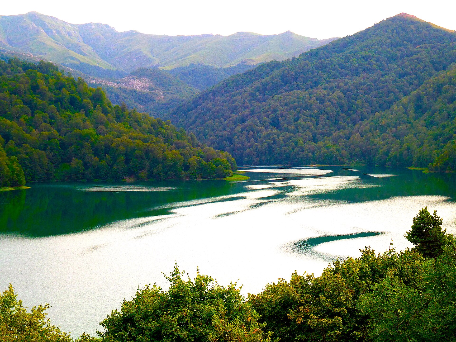 Deep green Goygol lake enclosed by forested mountain slopes