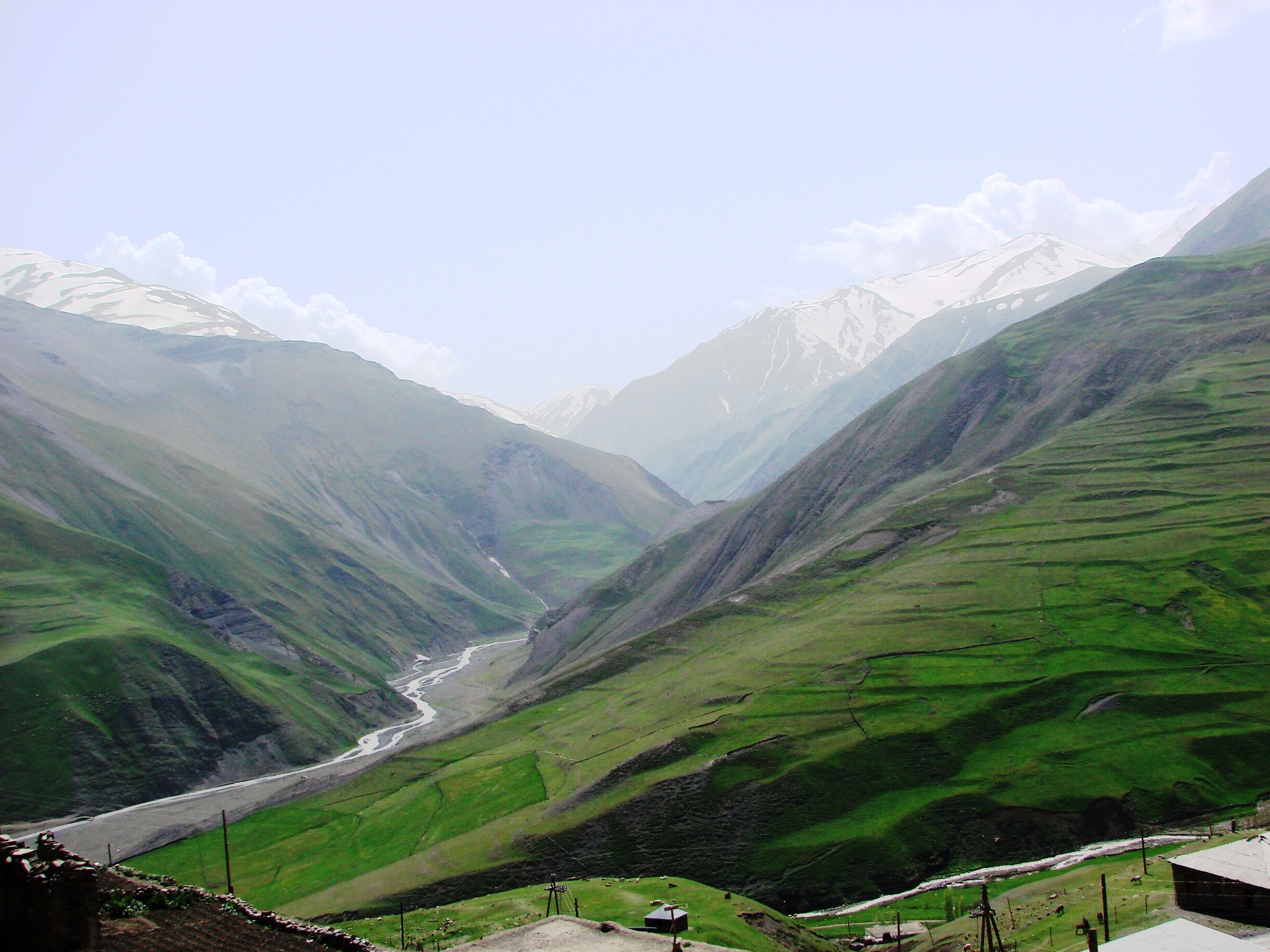 A green river valley cutting through high mountains below Khinalig