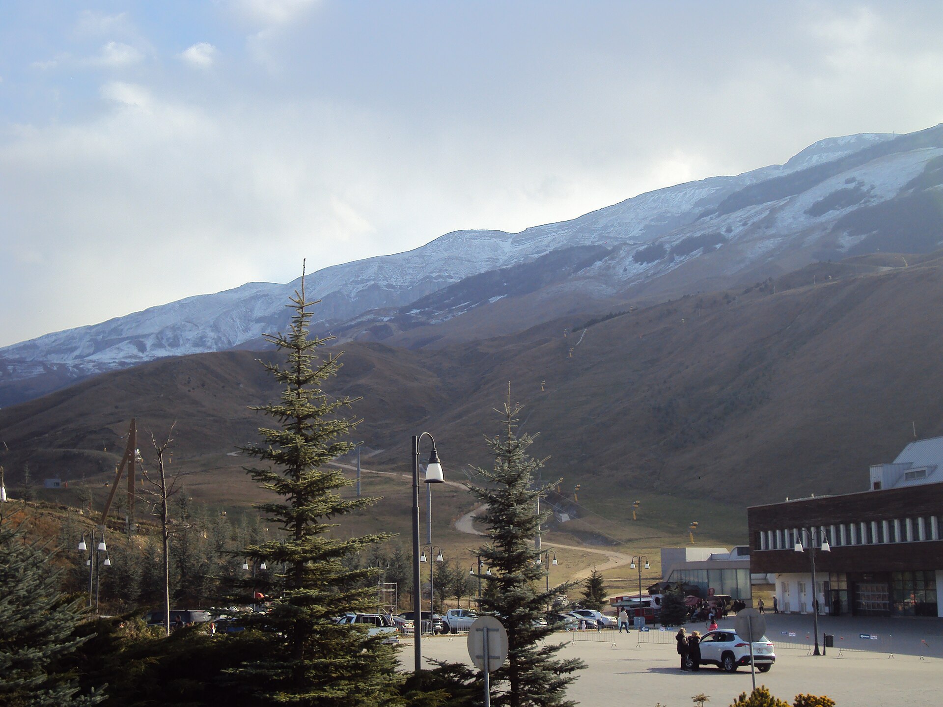 Hotels and young conifers beneath snow-covered slopes at Shahdag