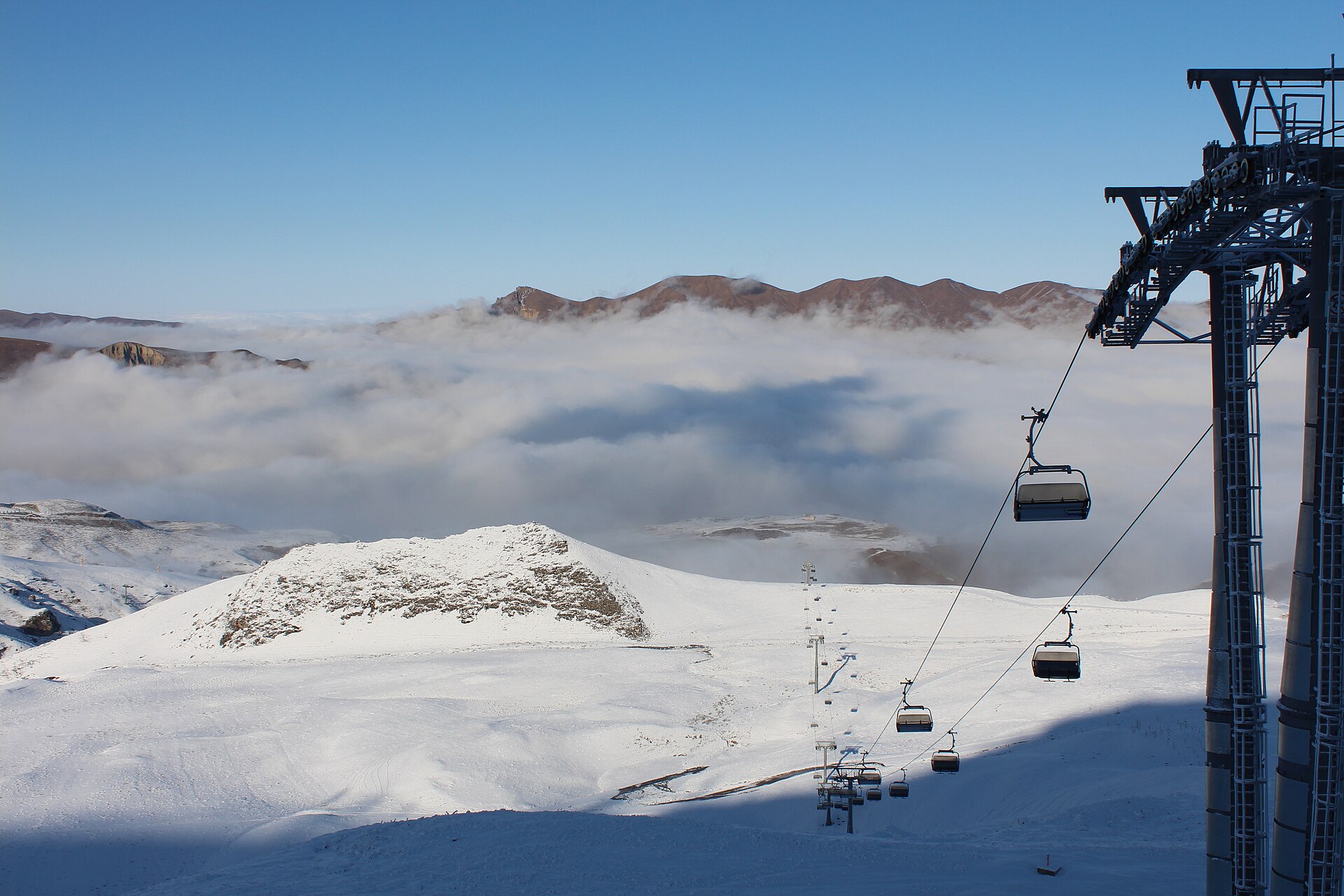 A cable car crossing snowy slopes above cloud at Shahdag