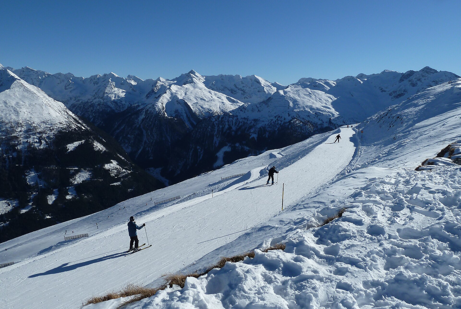 Skiers crossing a high snowy piste on Stubnerkogel above the Gastein valley