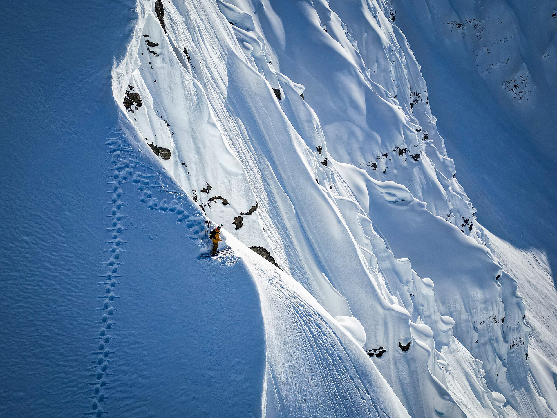 A skier traversing a steep snowy face in Alaska's Chugach Mountains