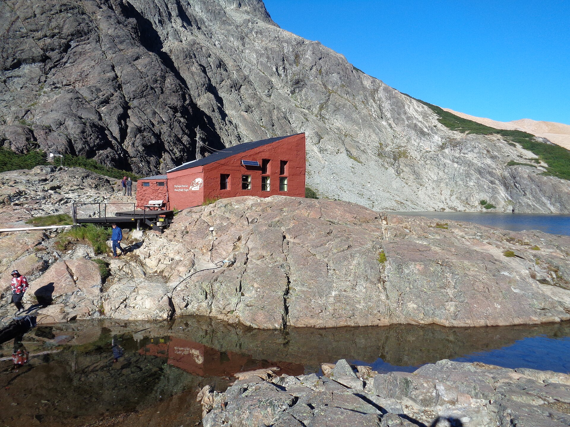 Le Refugio Italia, rouge, au bord de la sombre Laguna Negra et de parois rocheuses raides