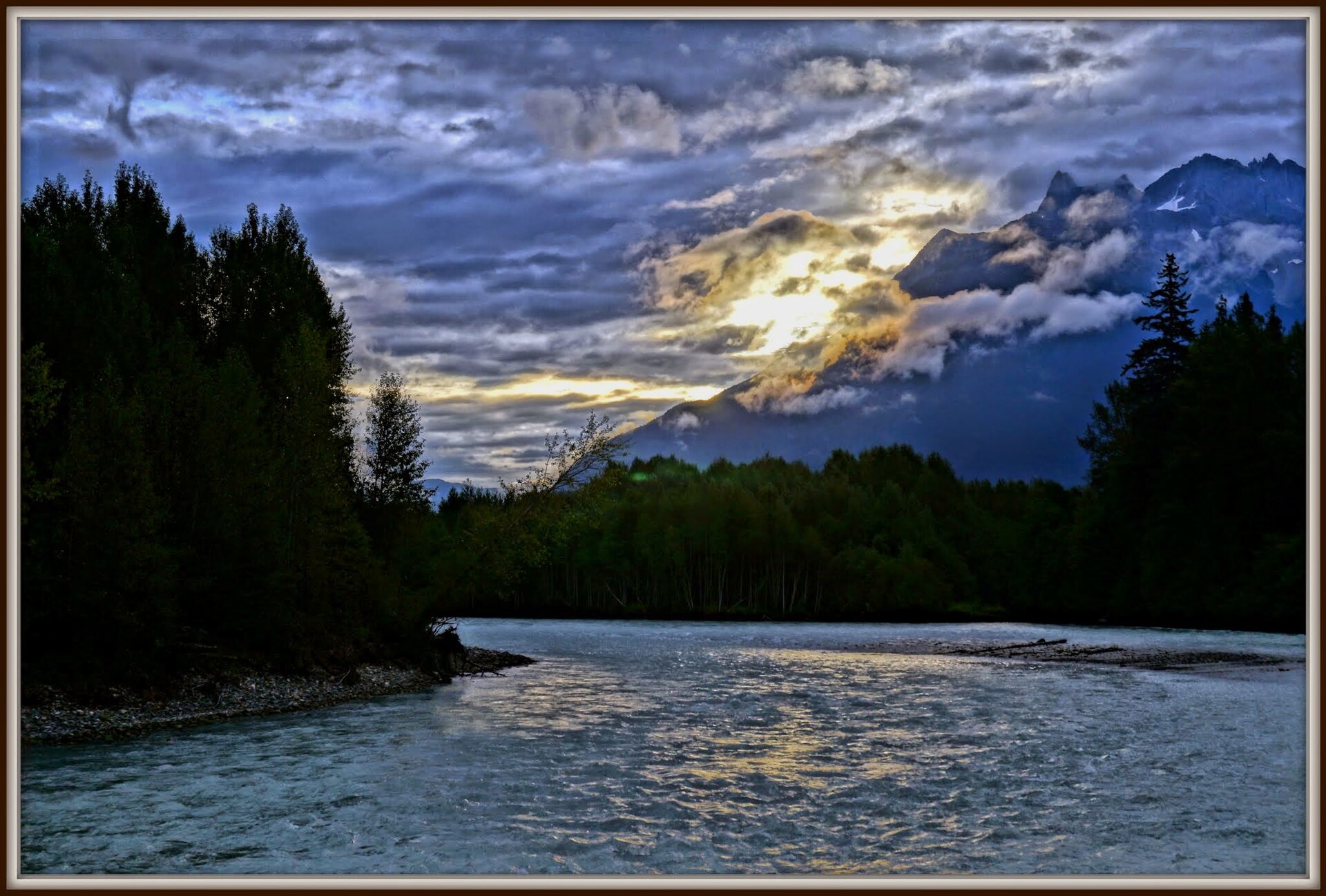 La rivière Bella Coola coulant sous des montagnes enveloppées de nuages