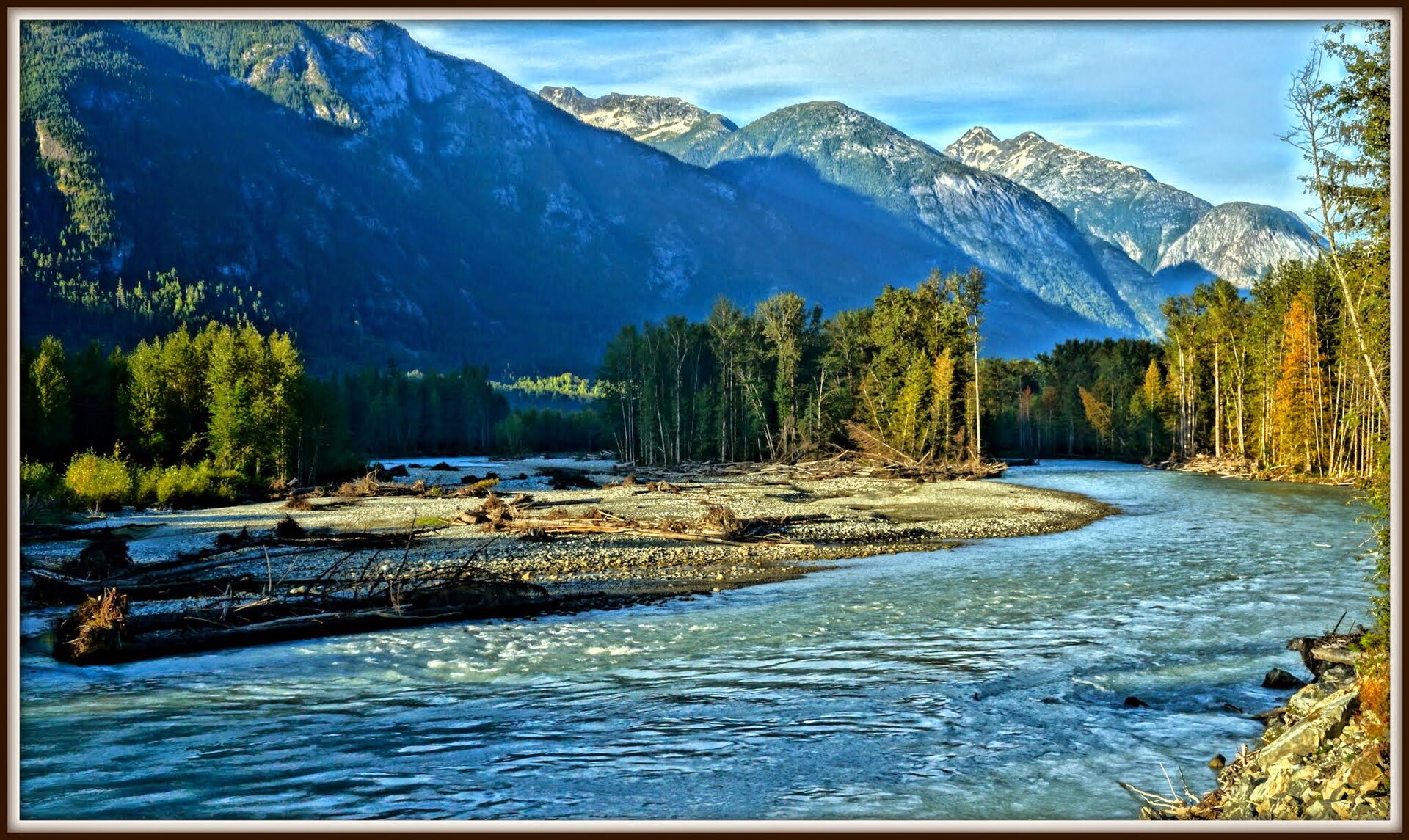 Un large lit de rivière en tresses traversant la vallée de Bella Coola sous des montagnes boisées