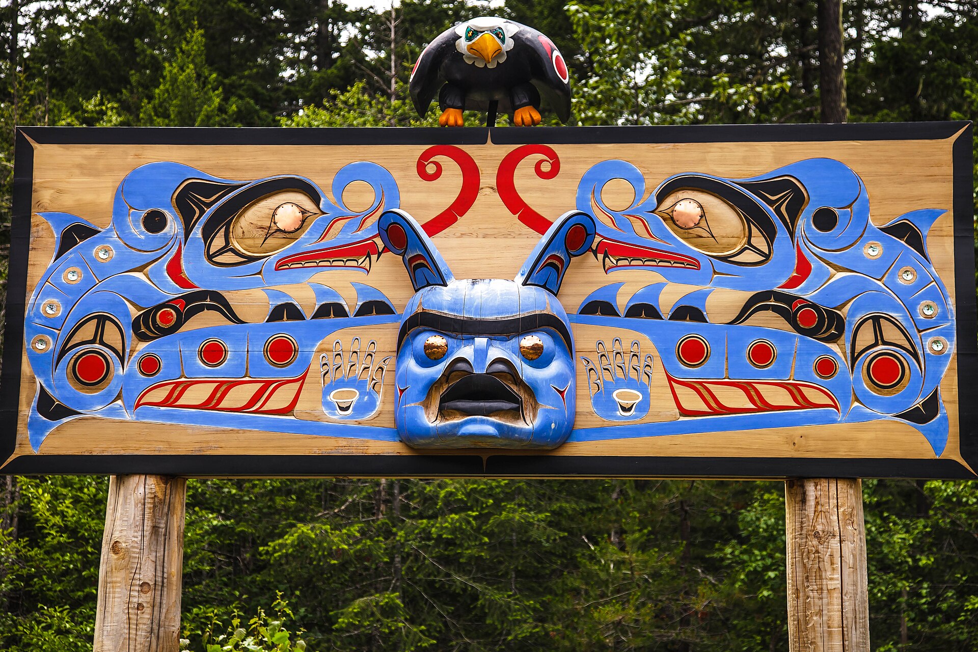 Un panneau commémoratif nuxalk sculpté et peint, surmonté d'un aigle, dans la vallée de Bella Coola