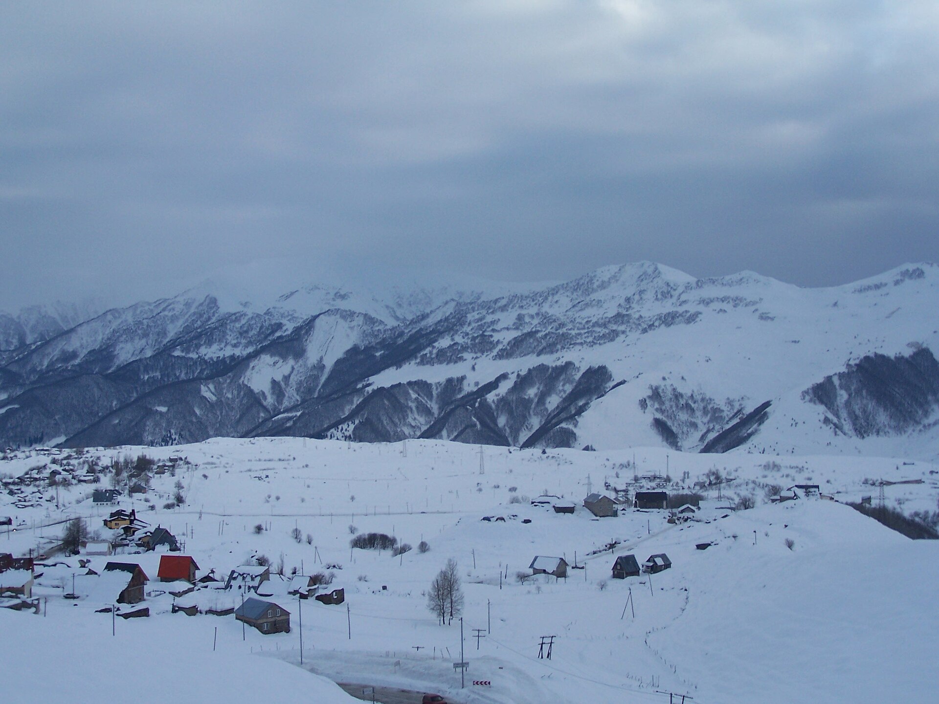 Snow-covered ridges and scattered buildings around Gudauri in winter