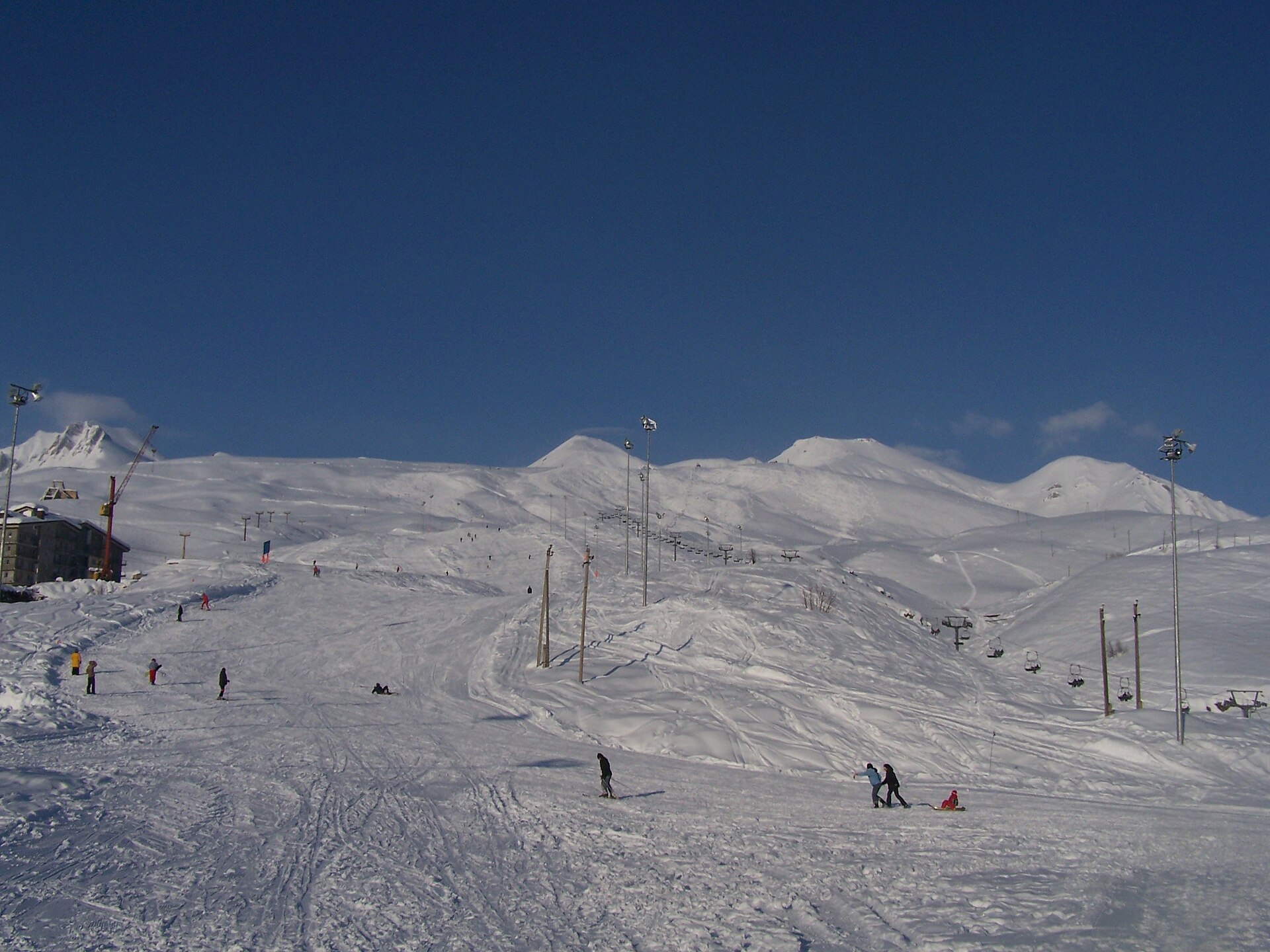 Skiers and lifts on the broad snow-covered slopes of Gudauri