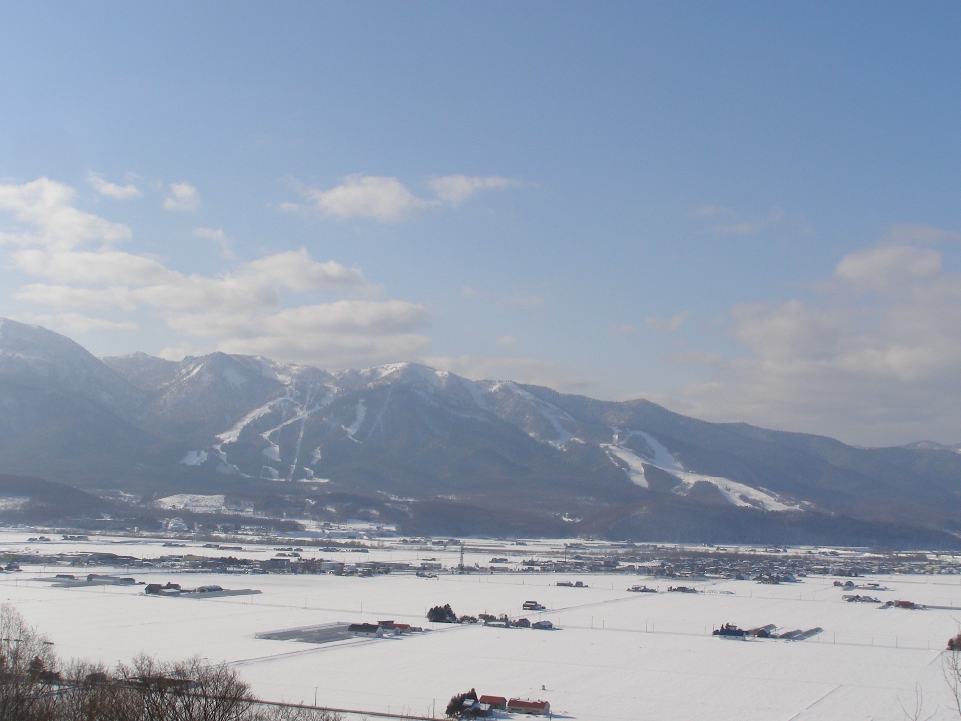 Furano town and snowfields beneath a long mountain range
