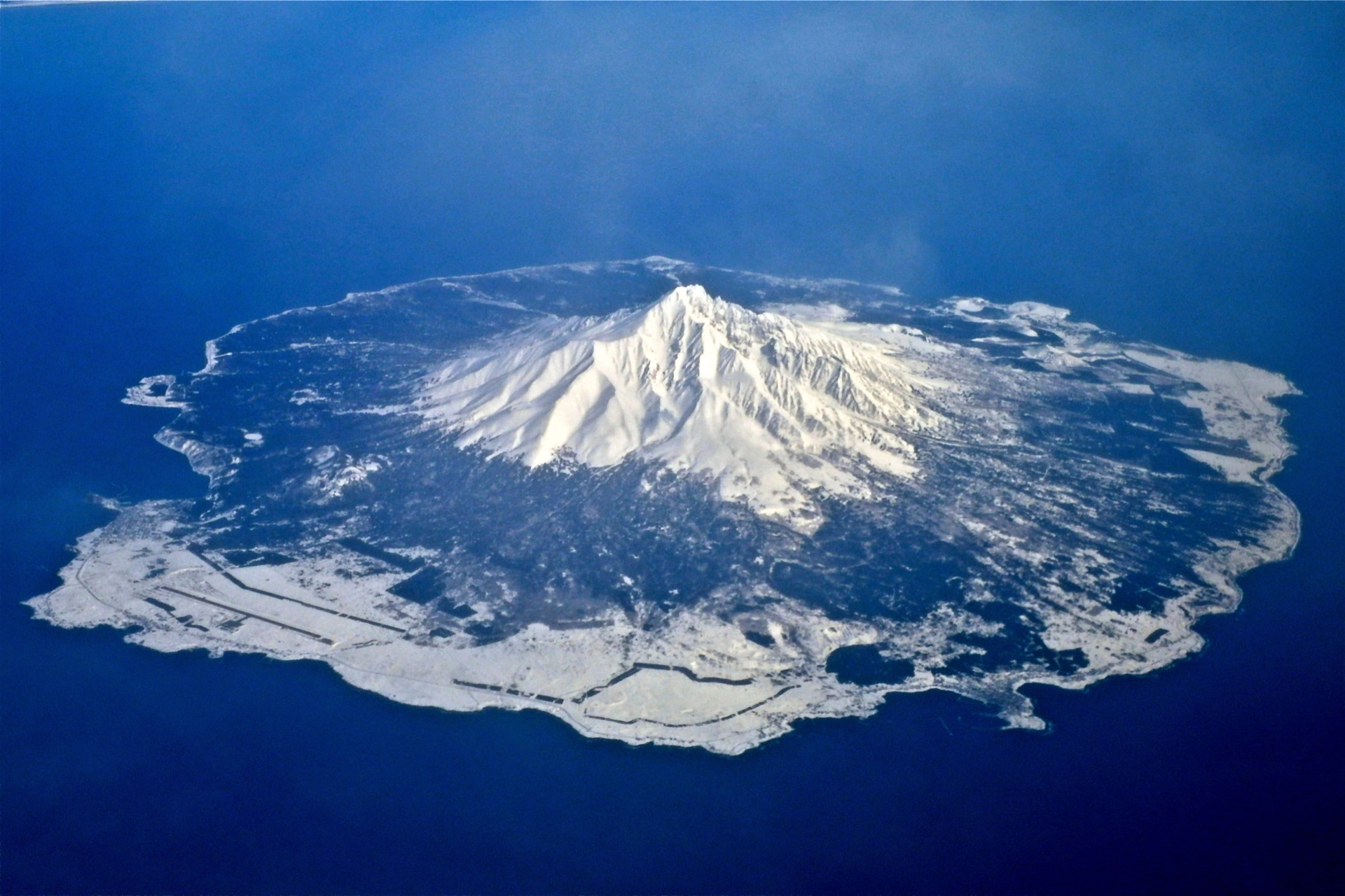 Aerial spring view of snow-covered Mount Rishiri surrounded by the Sea of Japan