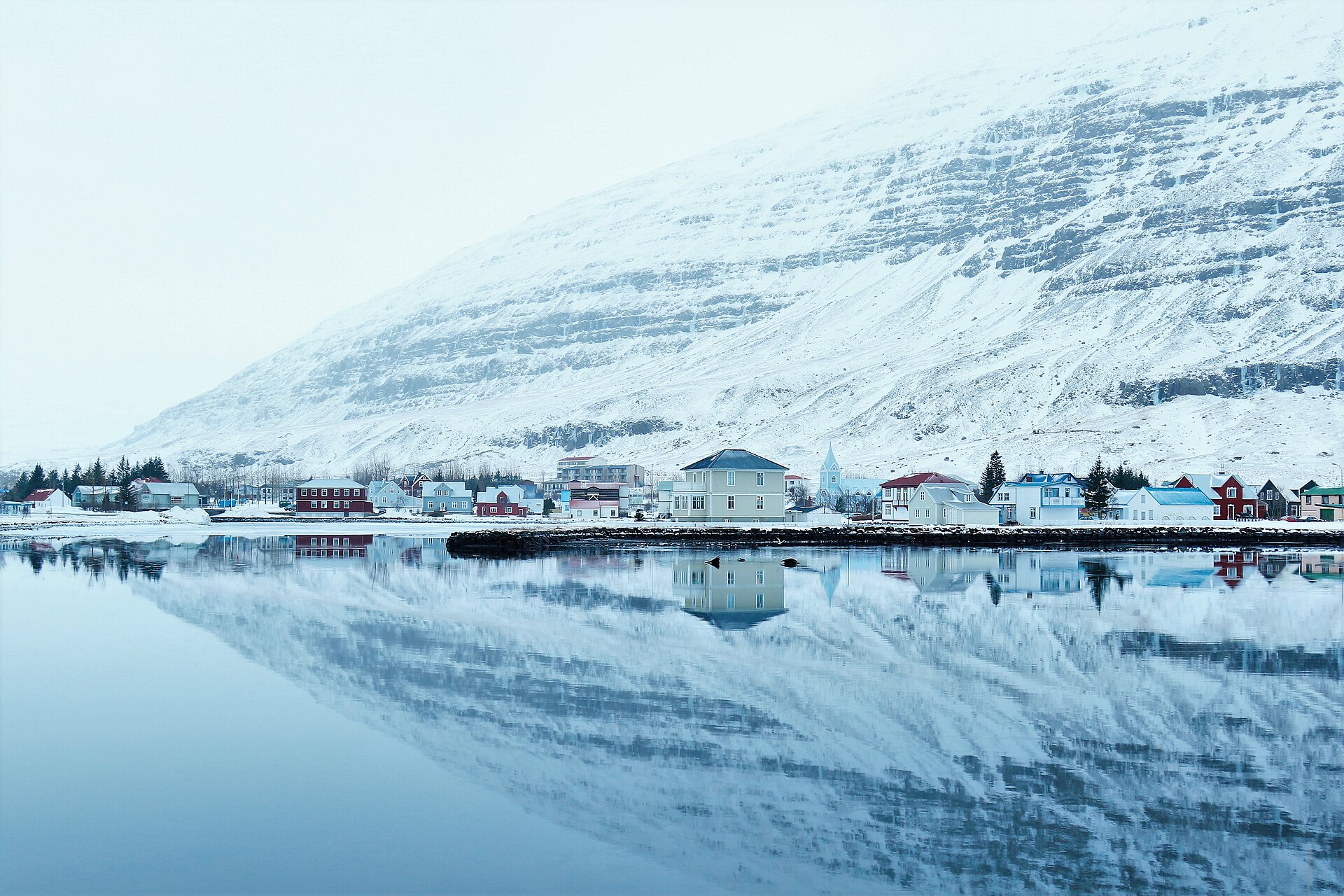 Seyðisfjörður and its snowy mountain reflected in still water