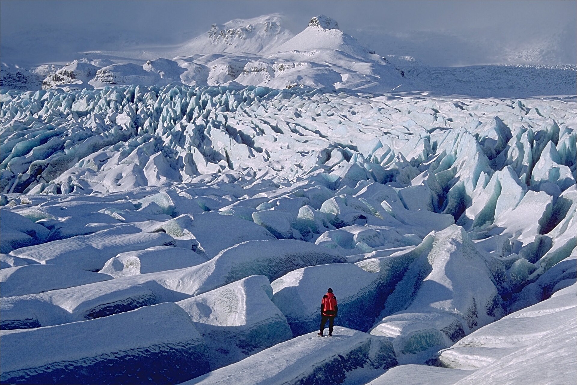 The broken blue ice of Breiðamerkurjökull below snowy mountains