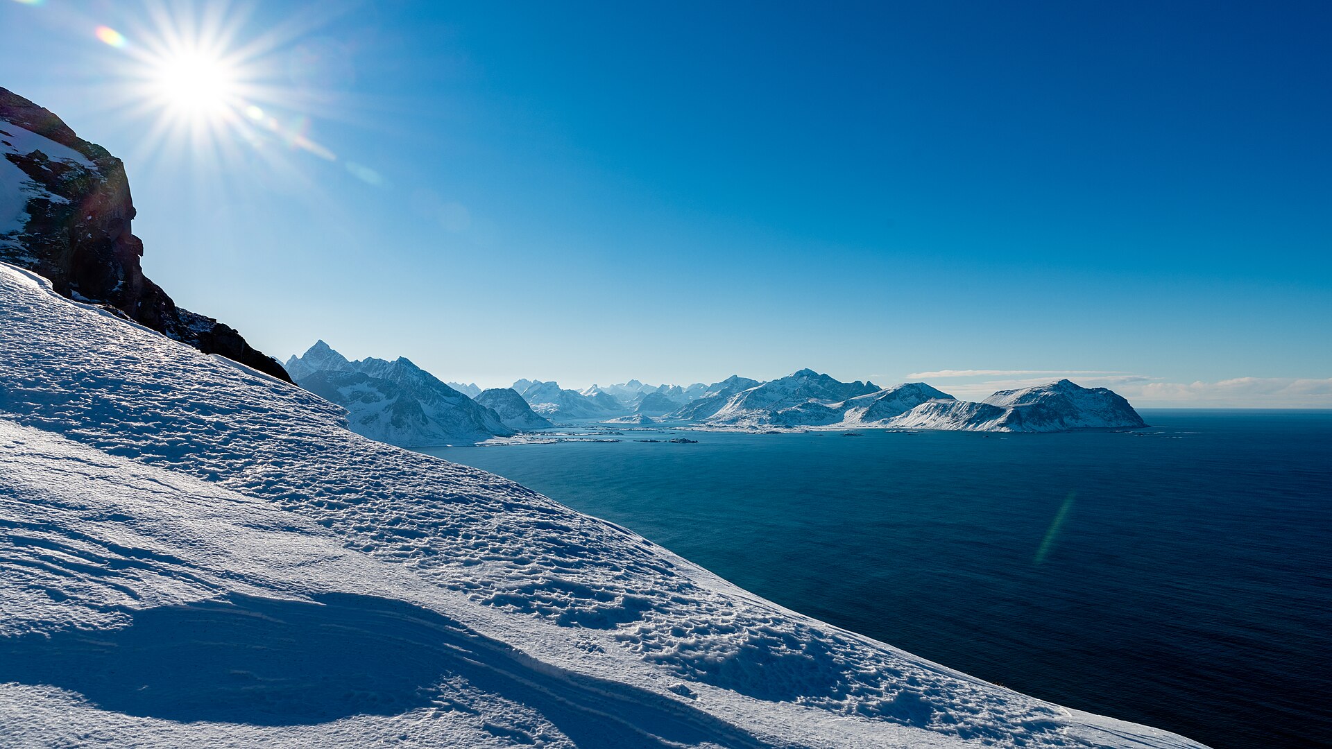 Snow-covered Lofoten mountains rising behind a winter shoreline