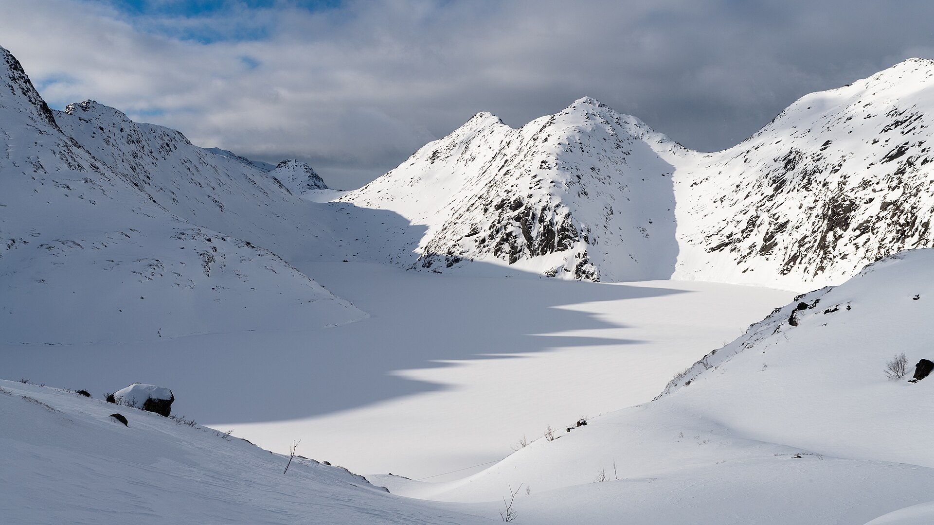 Frozen Stornøkkvatnet surrounded by snowy mountains in Lofoten
