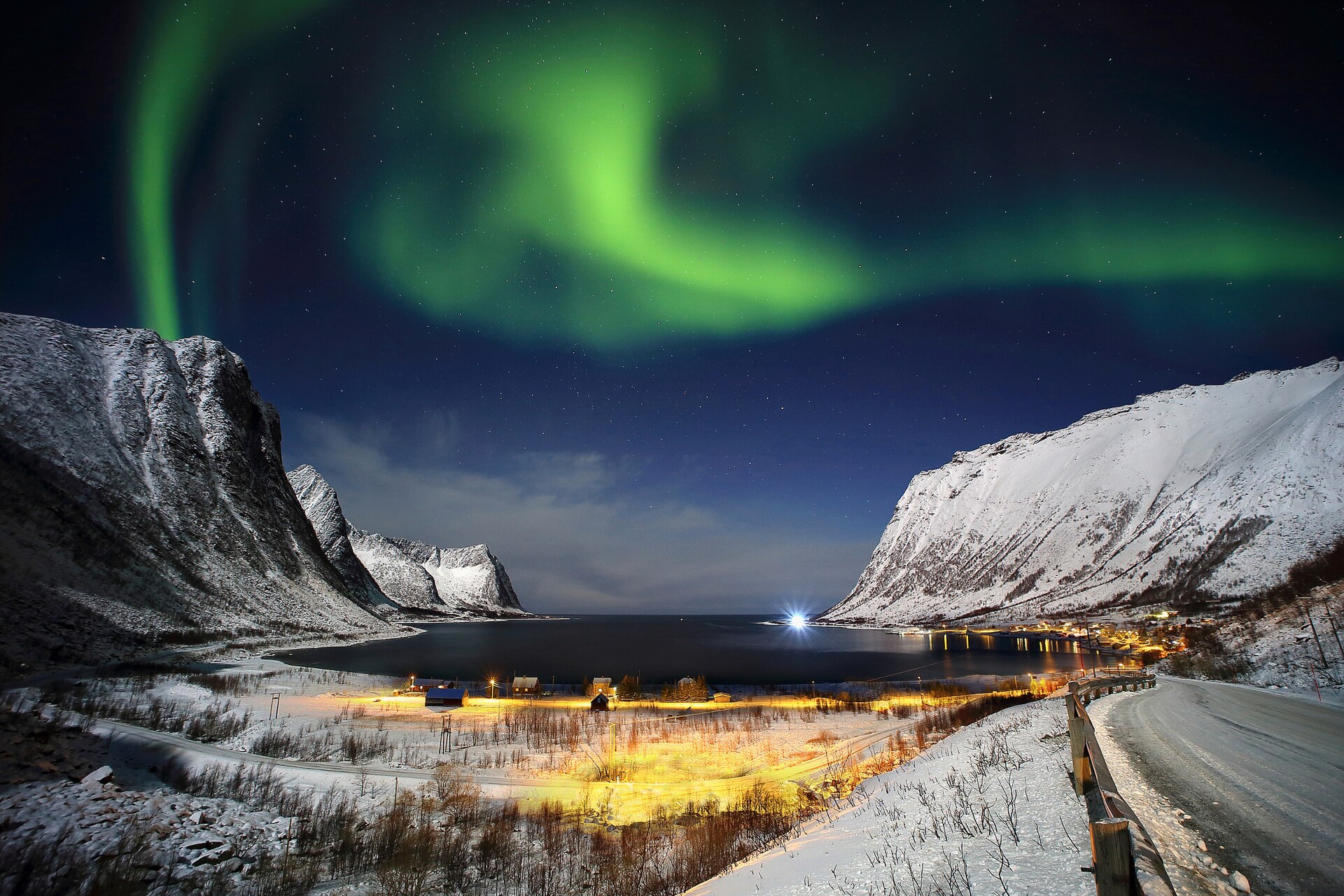 Aurora above the snowy mountains and village of Steinfjord on Senja