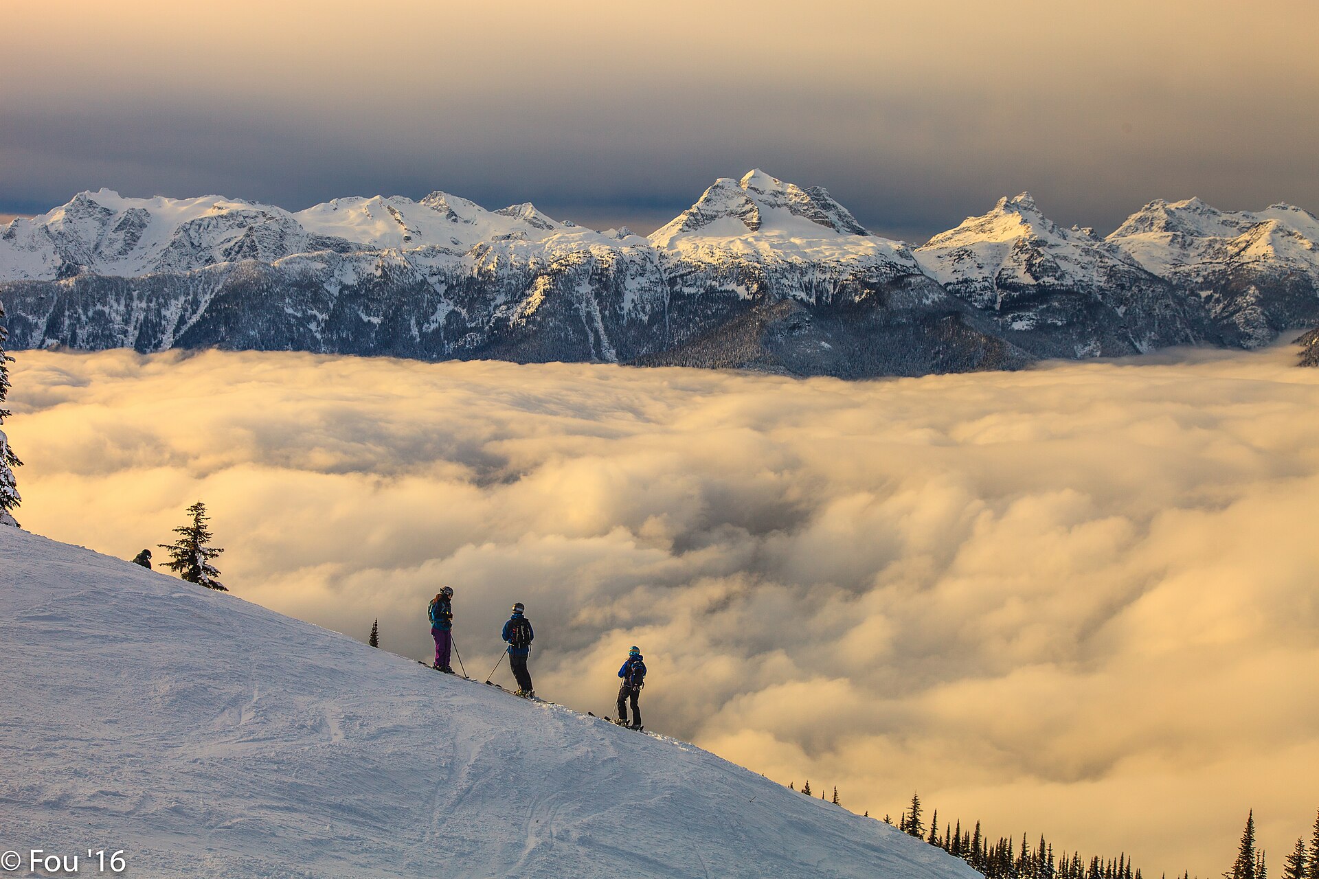 Des skieurs au-dessus d'une mer de nuages, avec le massif du mont Begbie à l'arrière-plan
