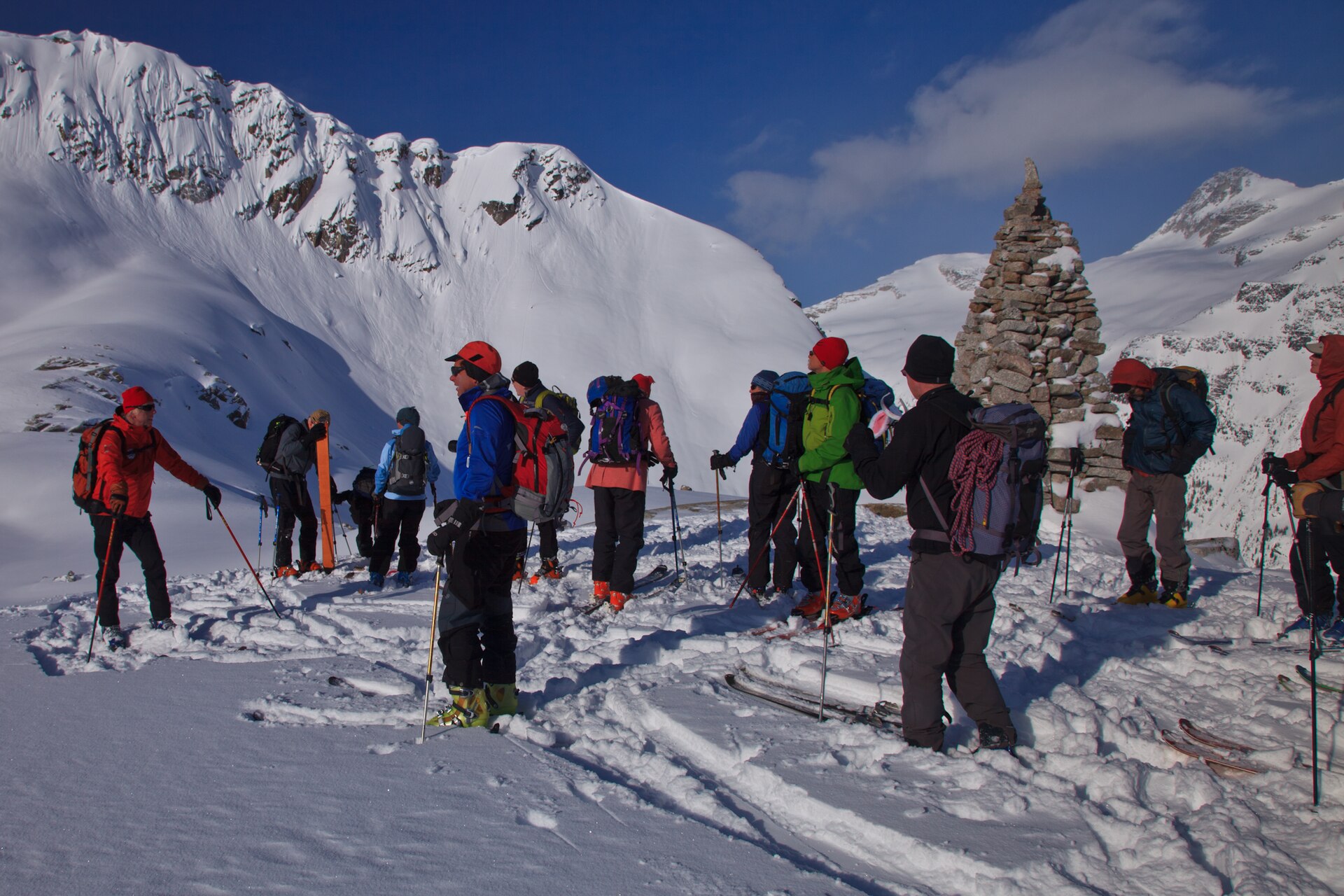 Des randonneurs à ski traversant un large bassin enneigé des Selkirk, près du glacier Omoo