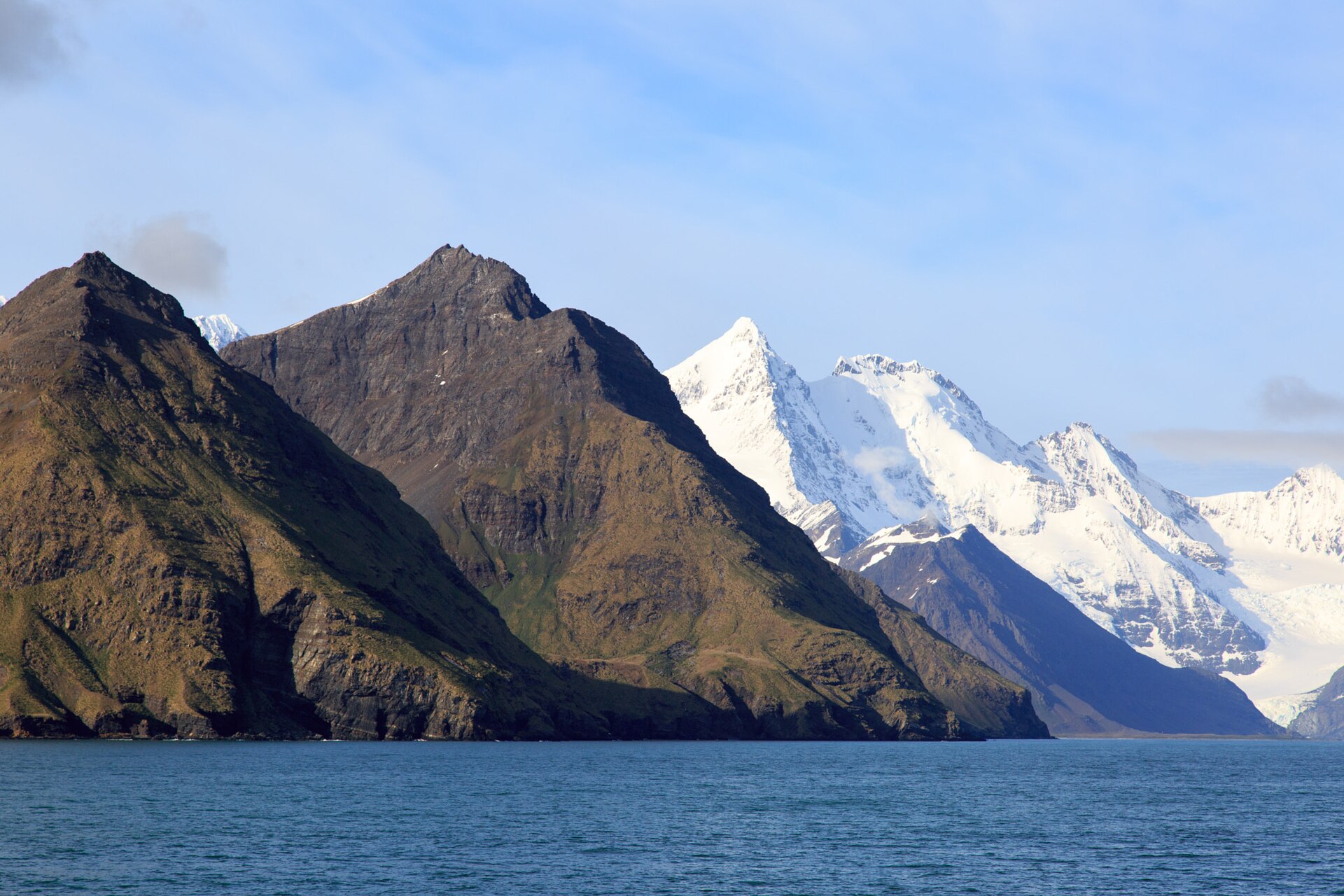 Layered dark ridges and snowy peaks rising directly from the sea in South Georgia