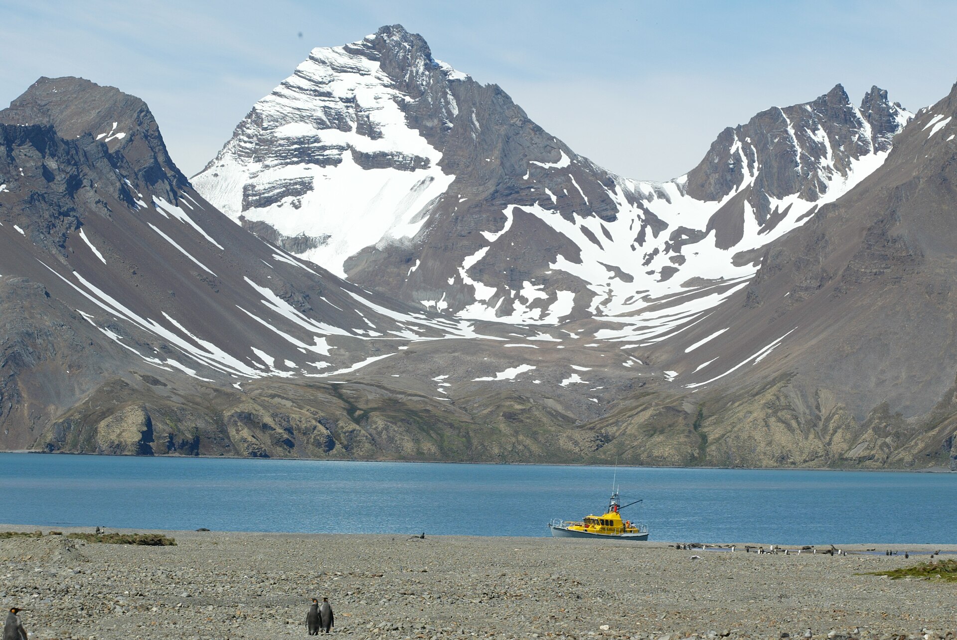 A steep snow-capped mountain above Fortuna Bay with a small boat near the shore