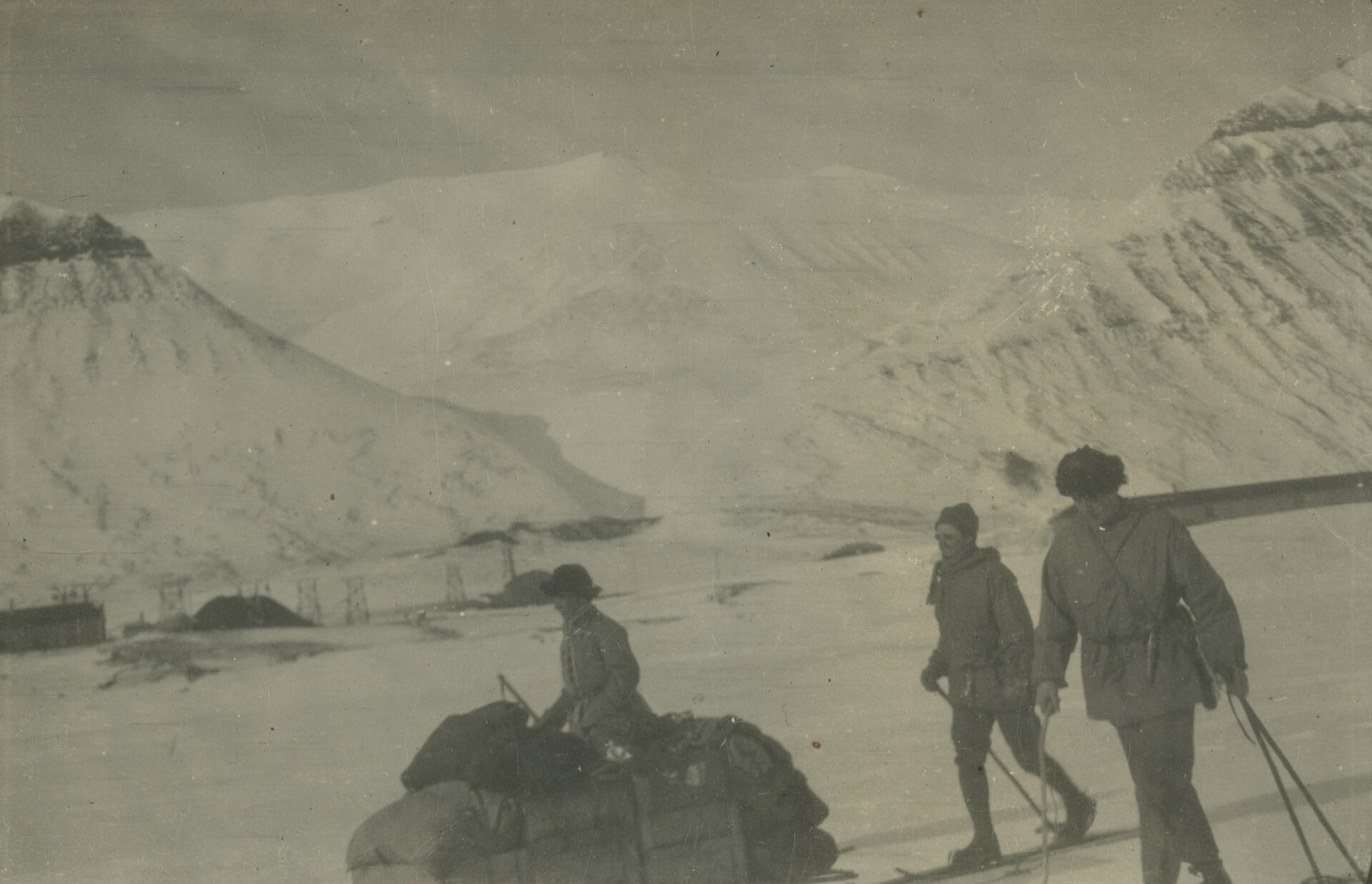 Historic Spitsbergen expedition members with skis and supplies in a snowy camp