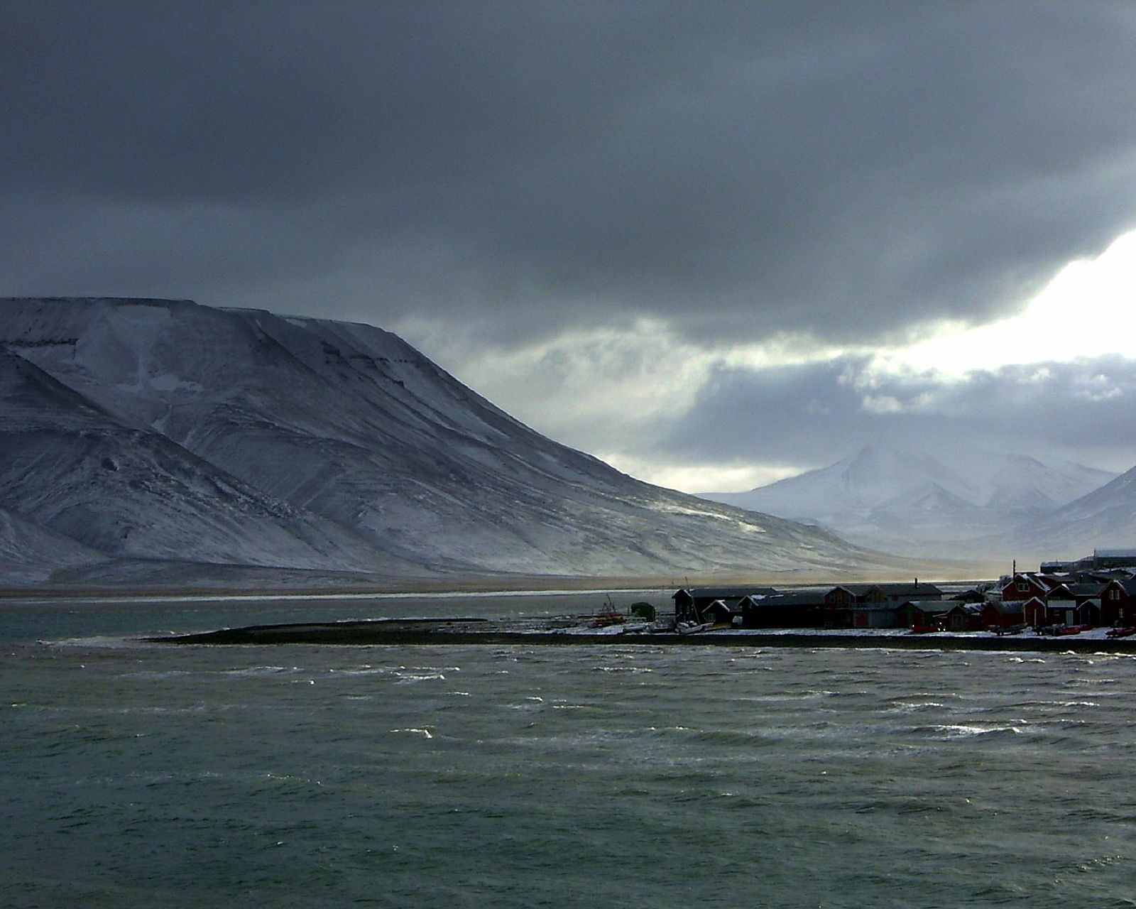 Longyearbyen beneath dark winter clouds and snow-covered mountains