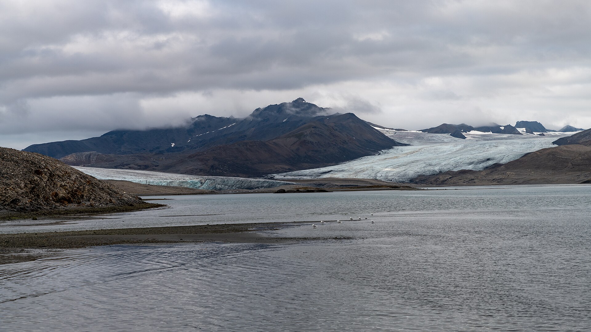 Glaciers and dark mountains enclosing Trygghamna Bay in Svalbard