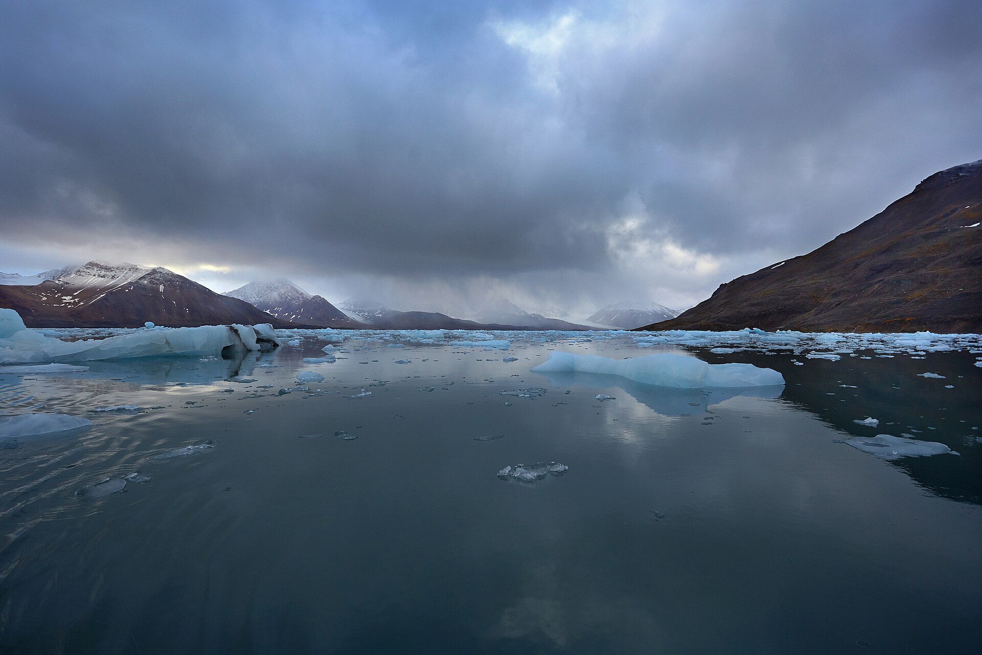 Glacier ice and steep mountains under storm clouds in St. Jonsfjorden