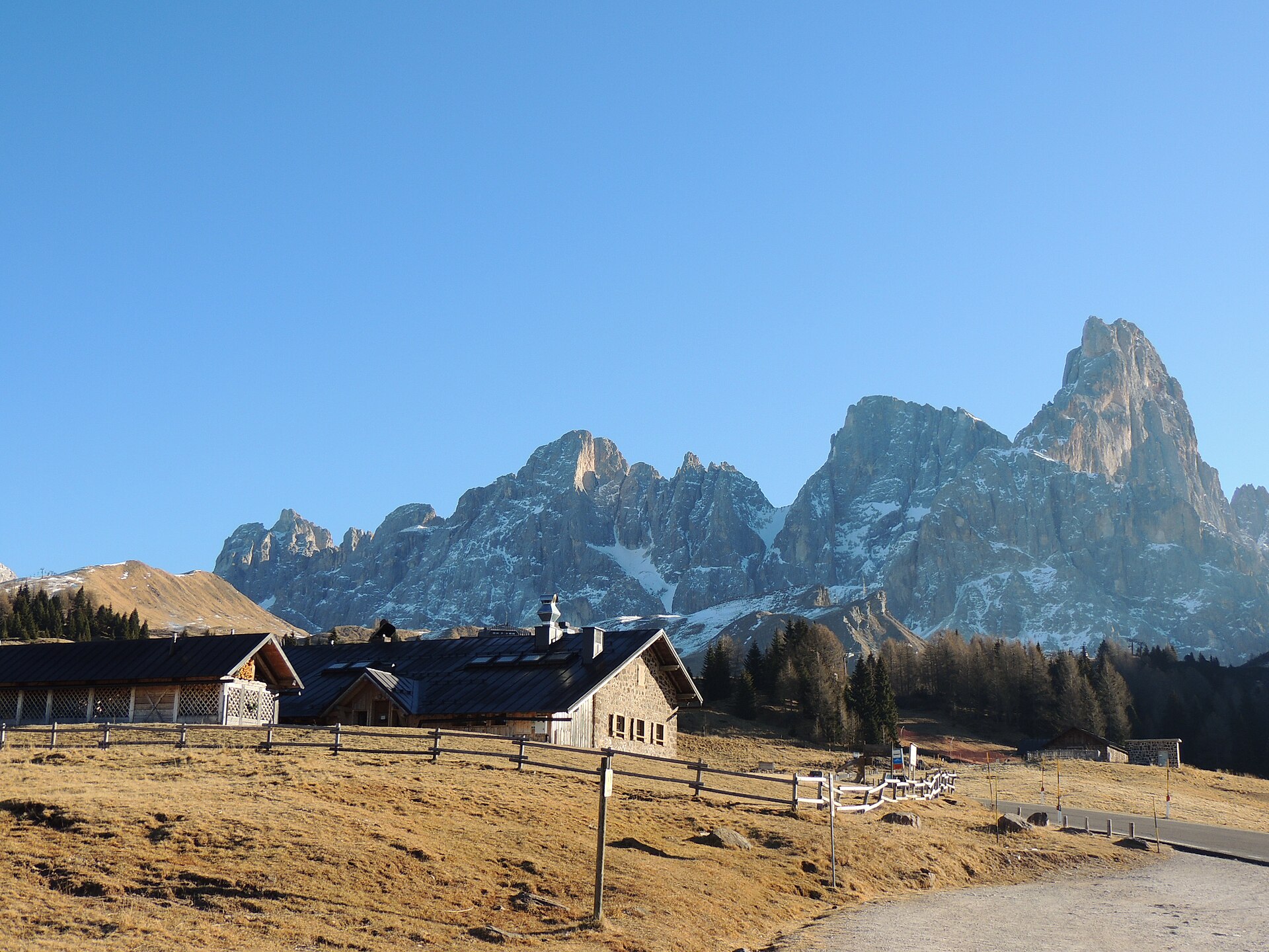 Le Cimon della Pala et les Pale di San Martino derrière les bâtiments et les pâturages dégagés du Passo Rolle