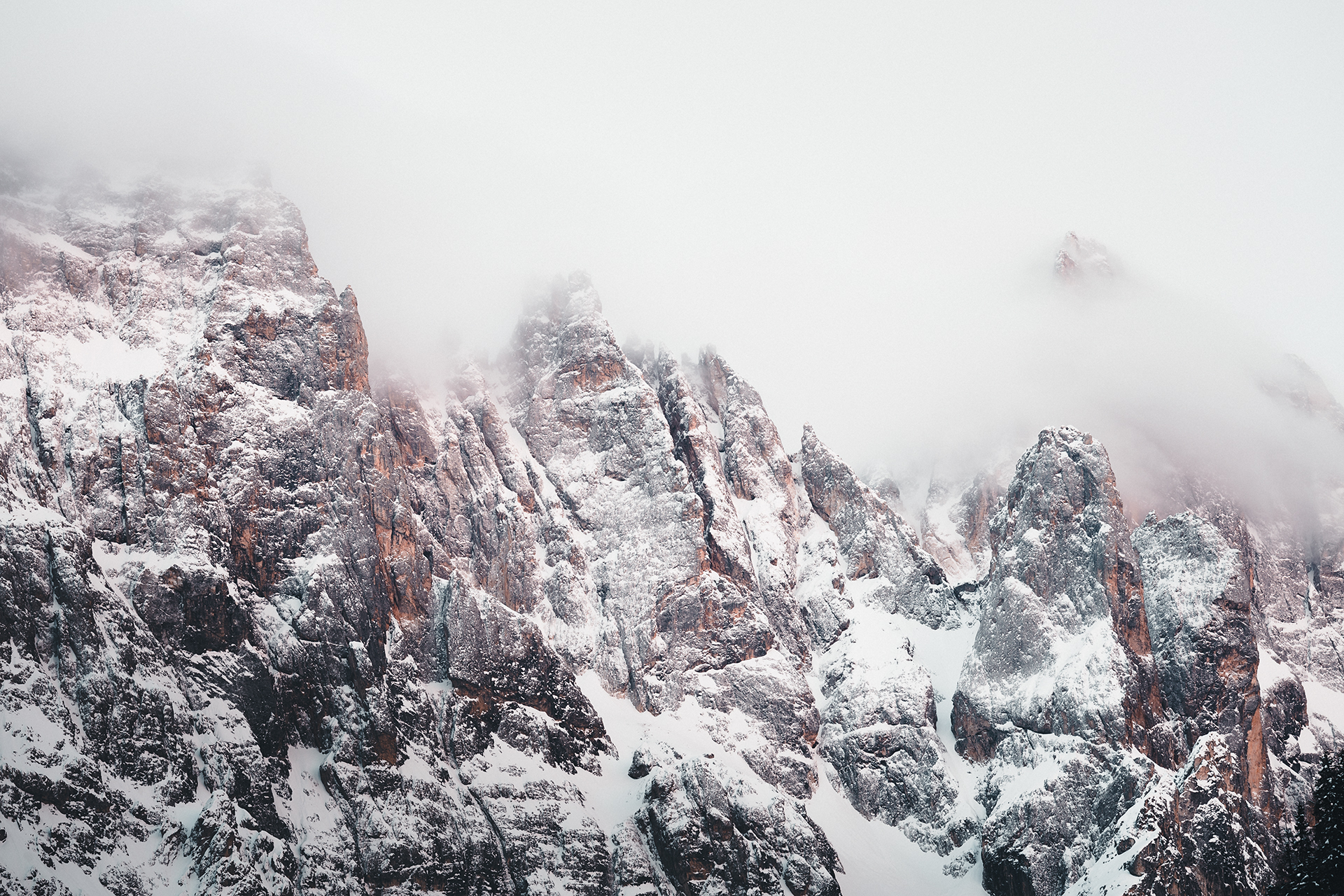 Tours rocheuses et ravines des Pale di San Martino, plaquées de neige et disparaissant dans les nuages