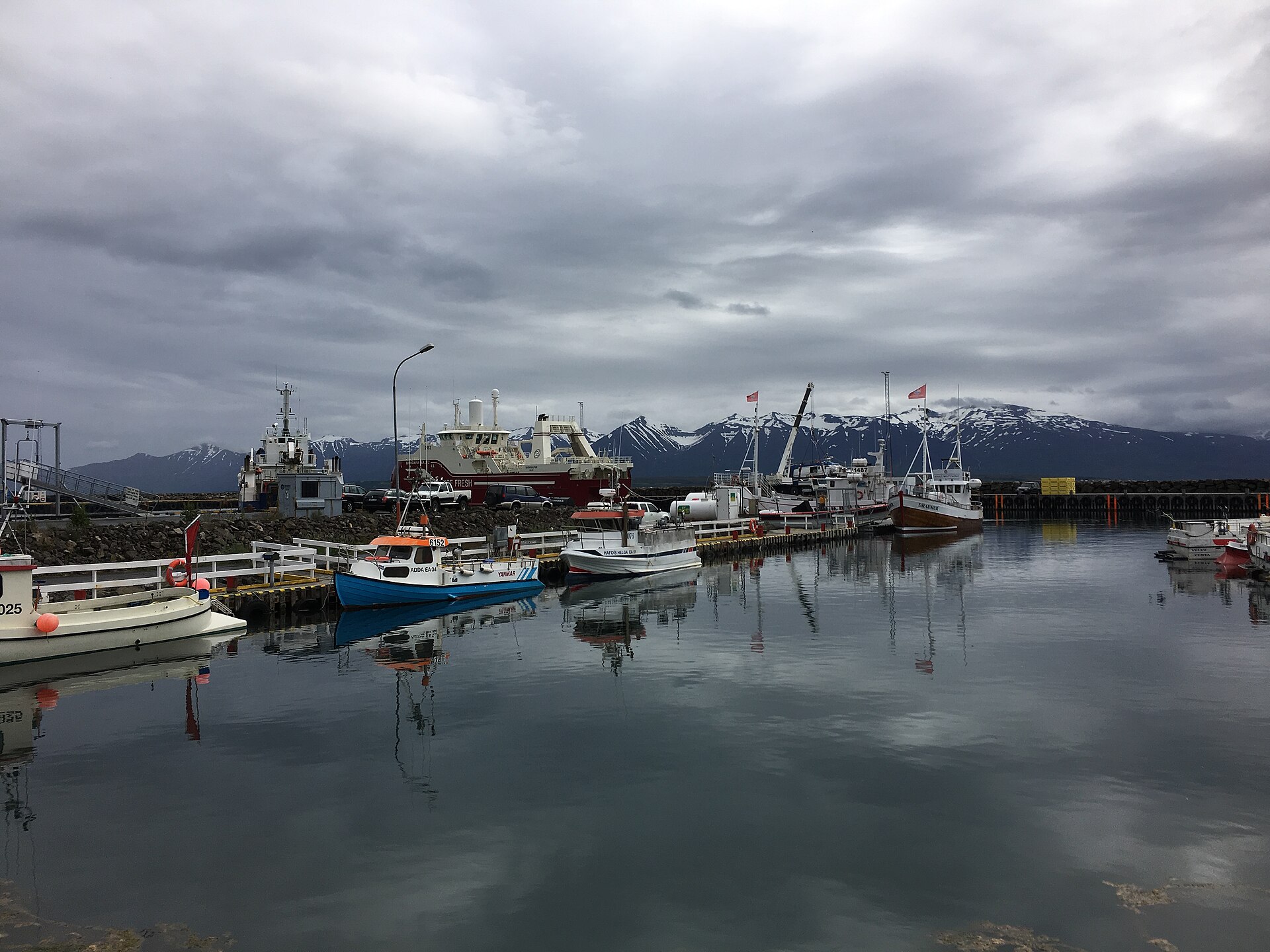 Fishing boats reflected in the calm marina at Dalvík beneath the mountains