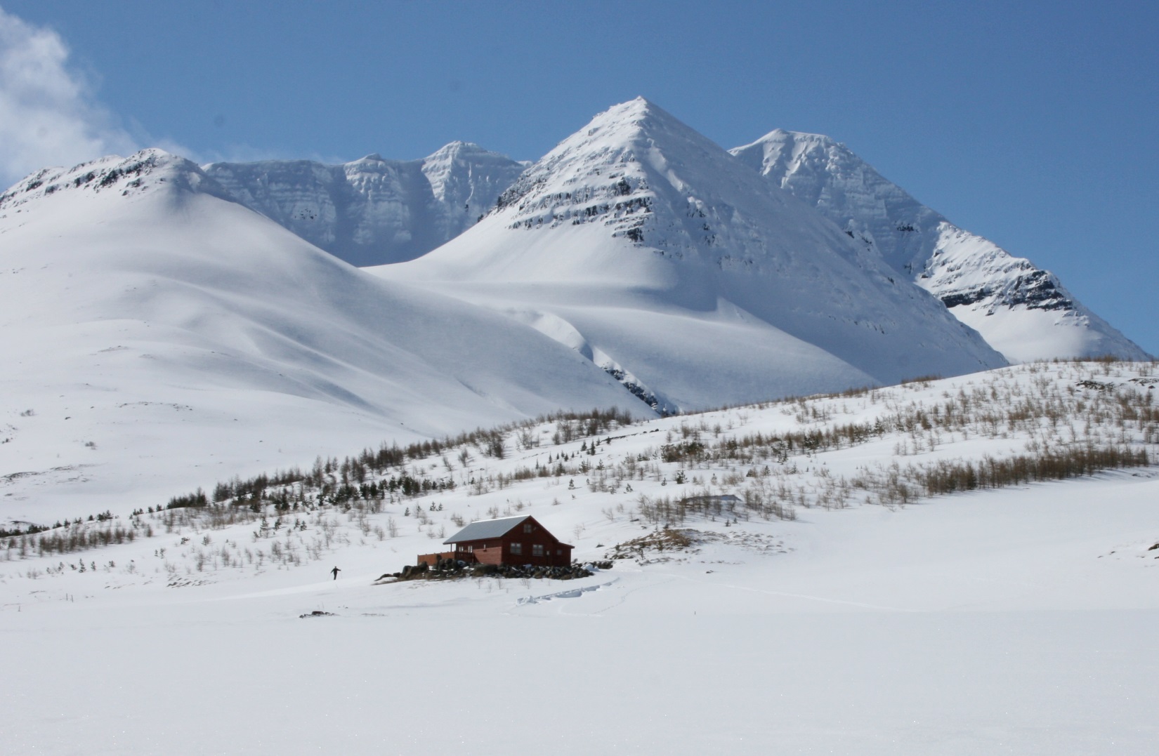 A red mountain lodge beneath the snow-covered ridges of Gloppuhnjúkur