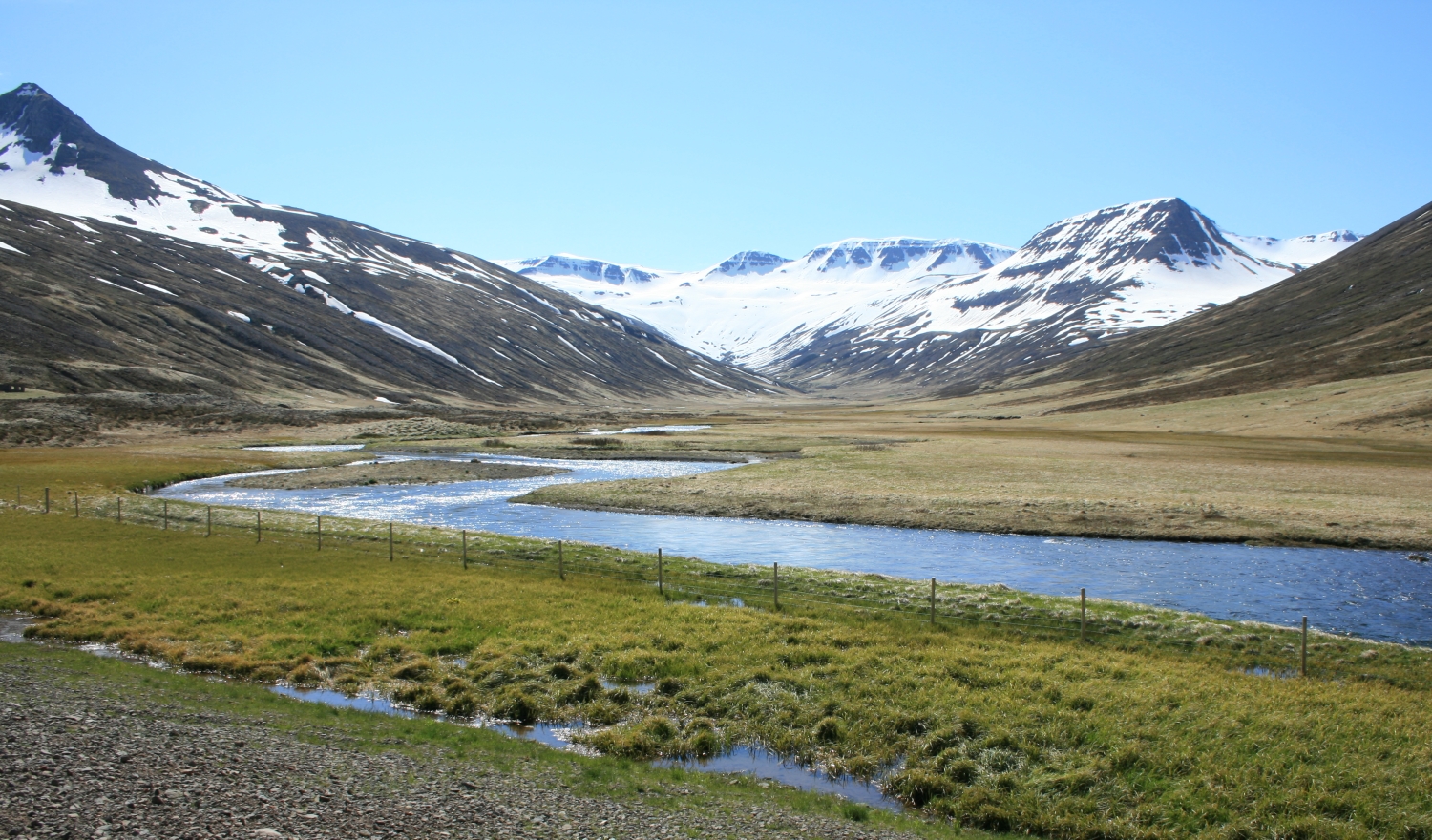 A river winding toward snow-lined mountains in Héðinsfjörður
