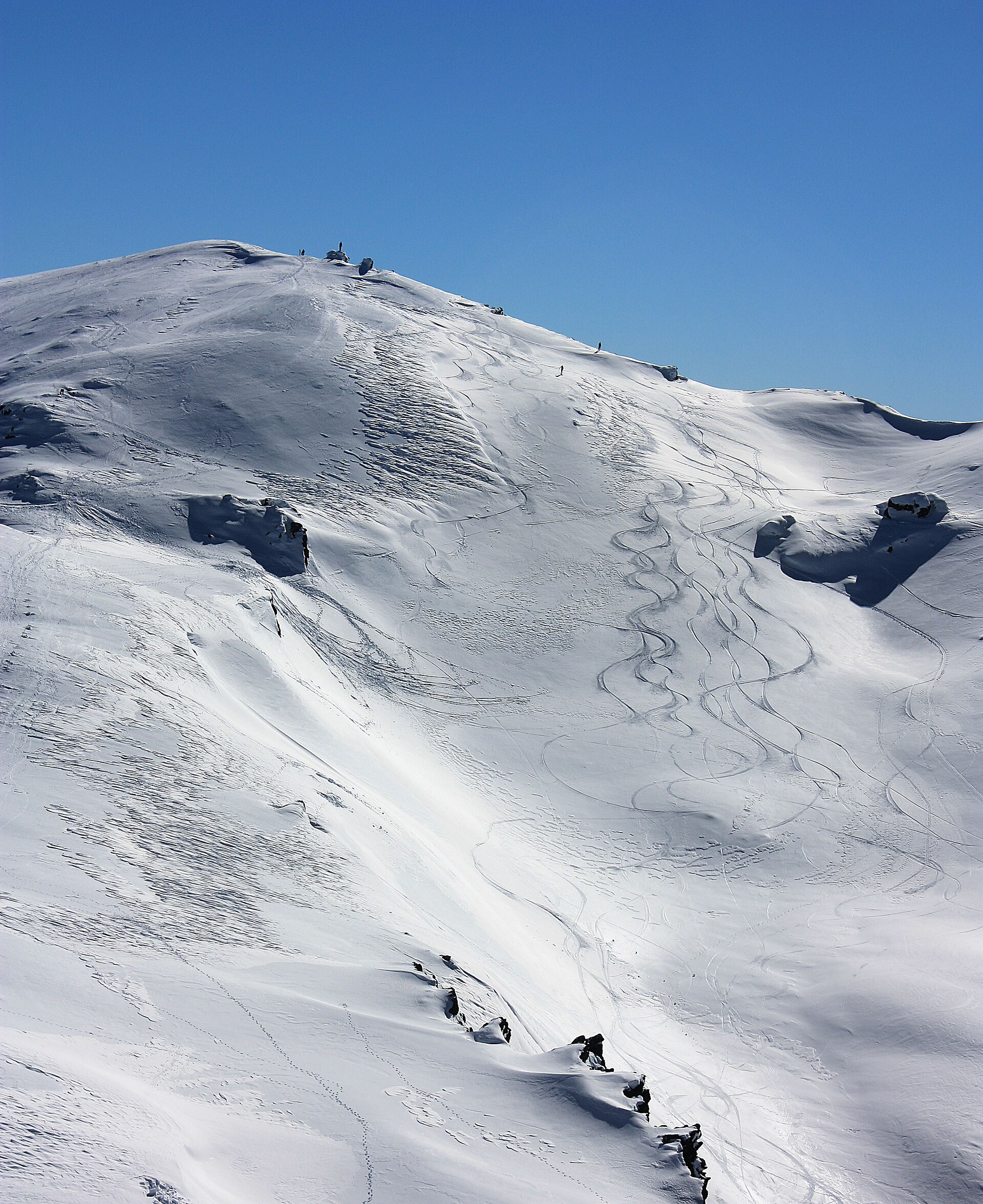 The snowy summit slopes of Mount Cardrona under a deep blue winter sky