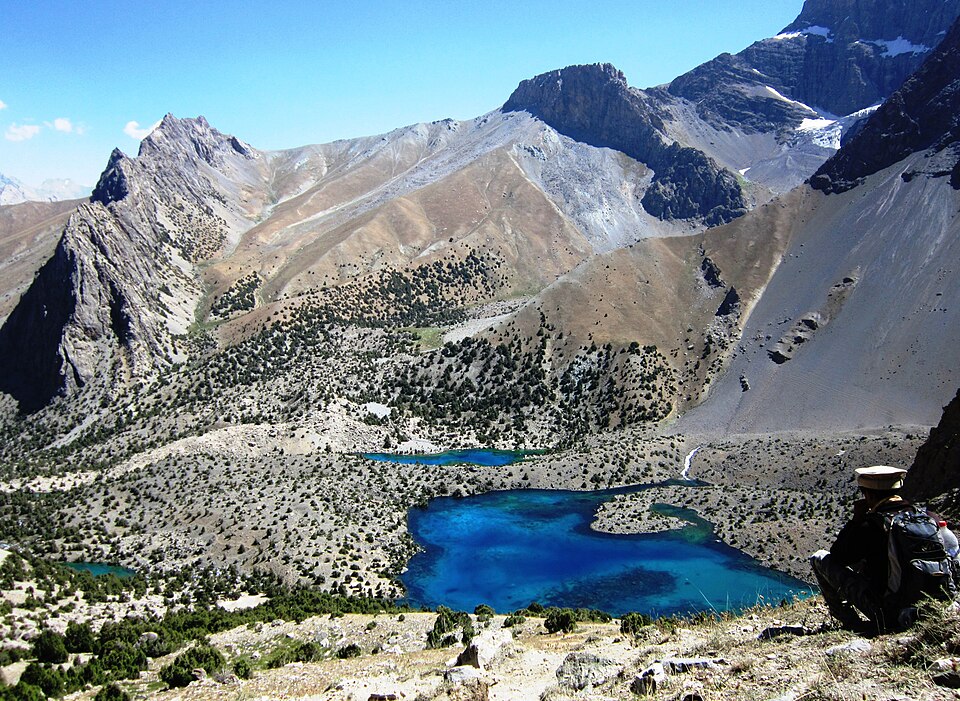 A vivid blue lake enclosed by steep peaks in the Fann Mountains