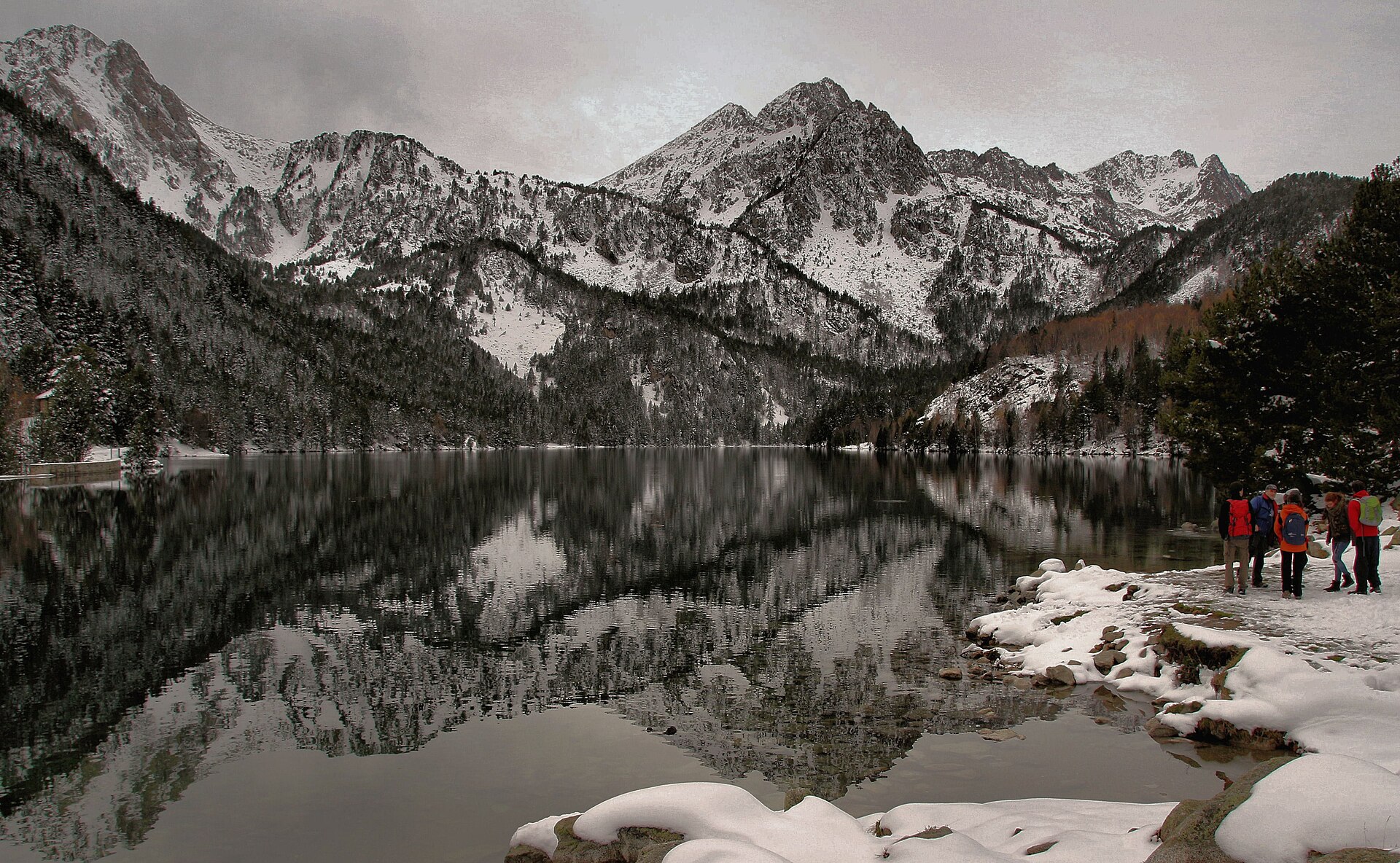 Frozen, snow-fringed Sant Maurici lake beneath serrated mountains