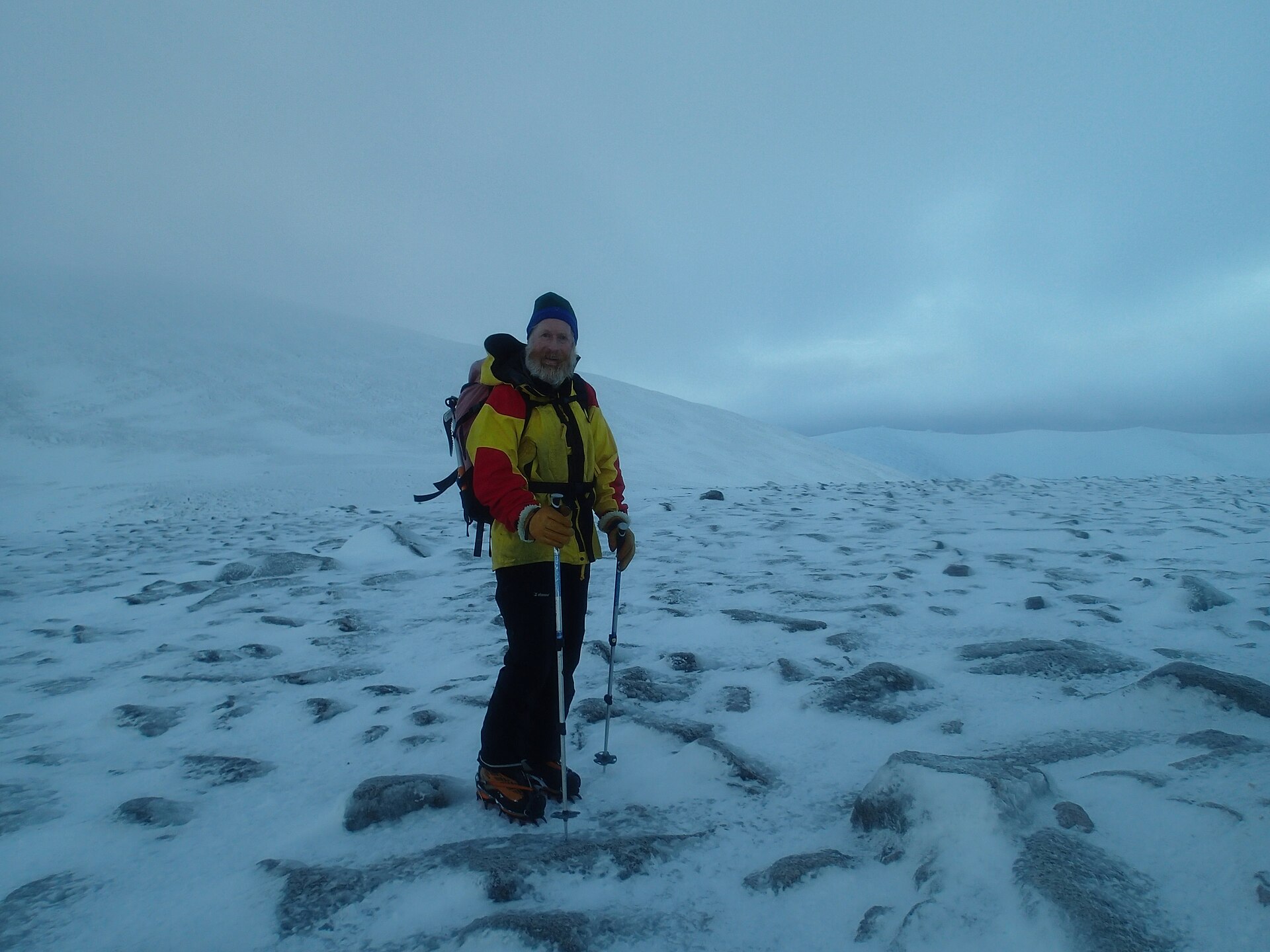 A winter mountaineer navigating across a snowy Cairngorm plateau