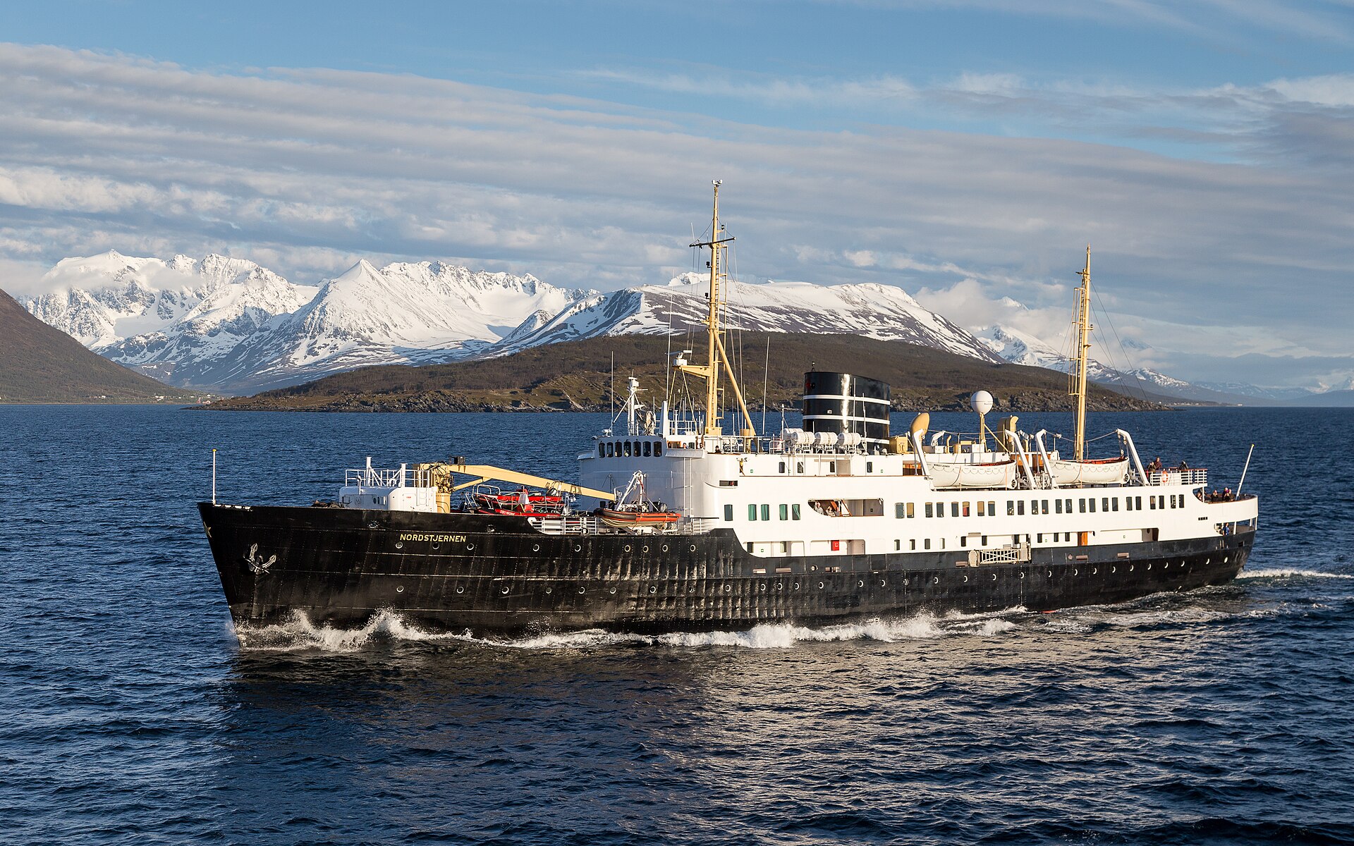 A passenger ship crossing Lyngen fjord beneath snowy mountains