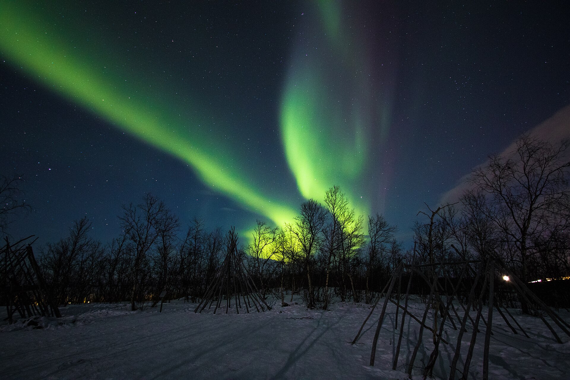 Green aurora above snowy mountains near Abisko