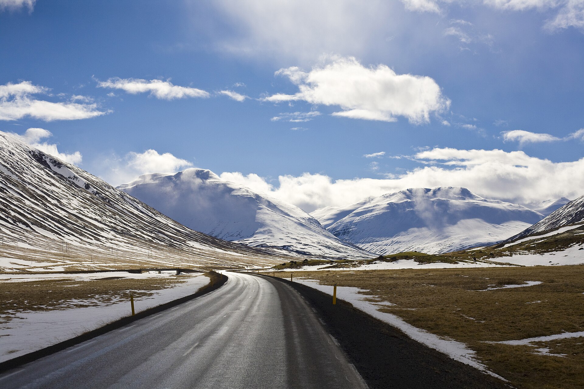 A road crossing a snowy valley between mountains in northern Iceland