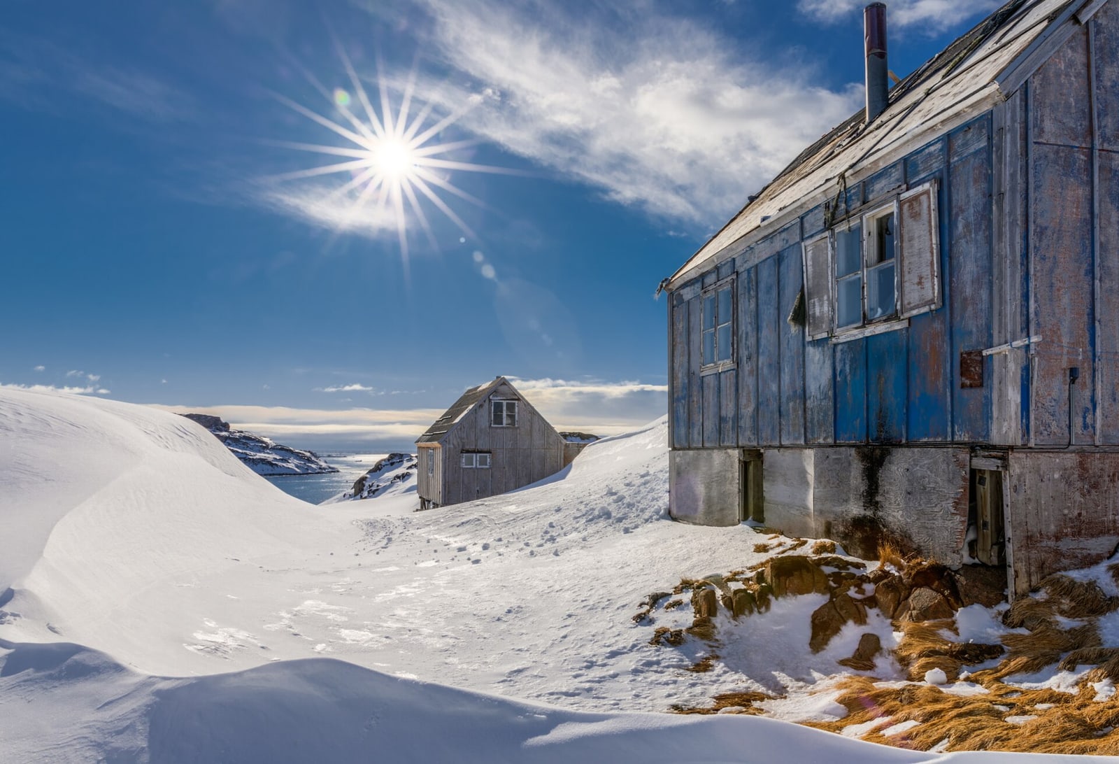 Colourful houses in Kulusuk beneath snowy mountains