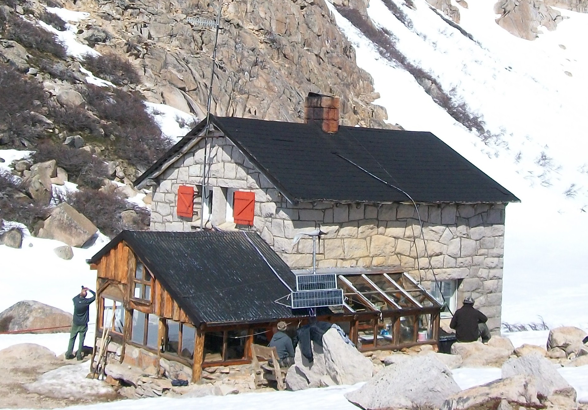The stone Refugio Frey surrounded by snow and steep granite walls