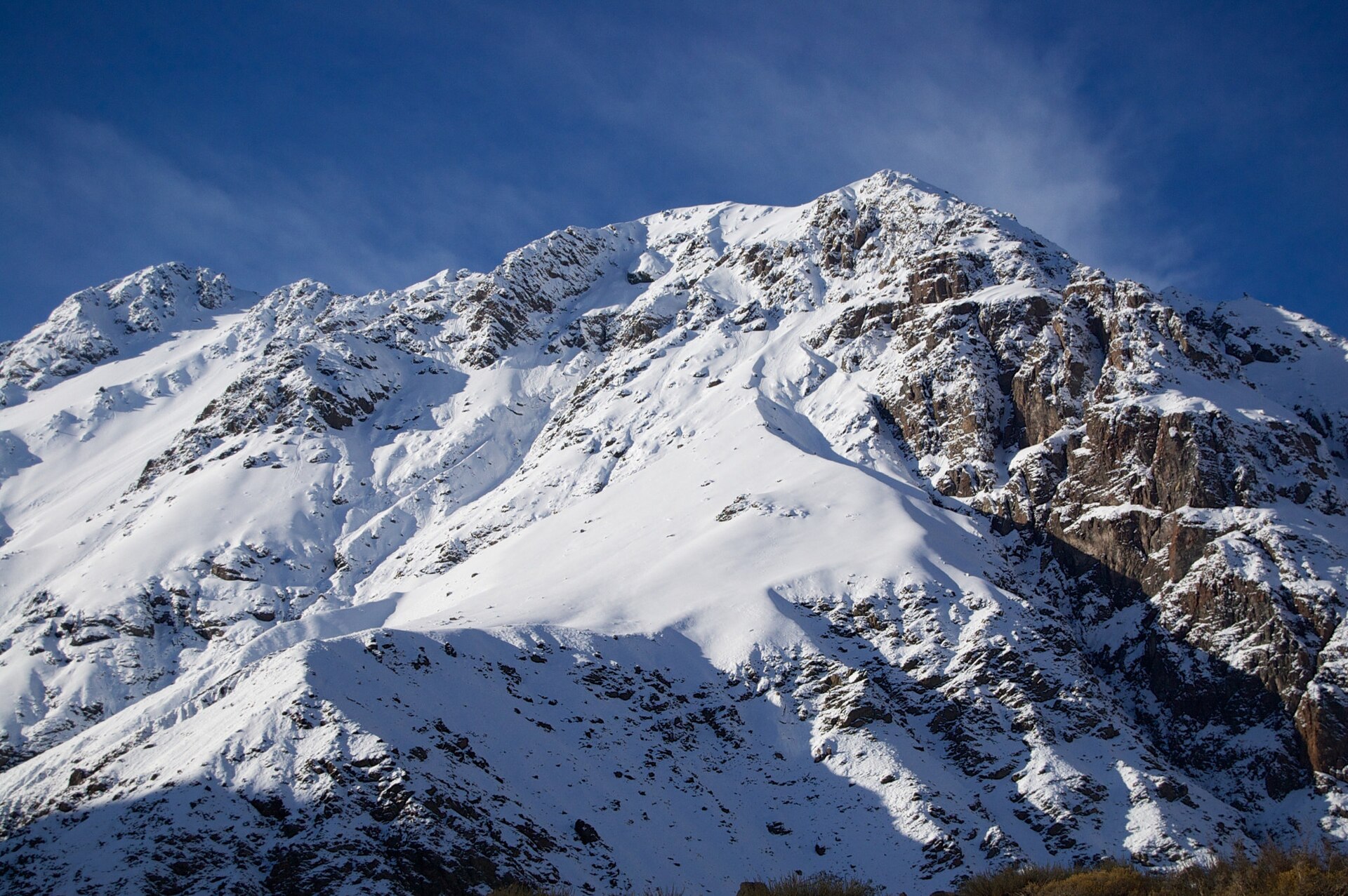 Steep snow-covered mountain walls beneath a blue sky in Cajón del Maipo